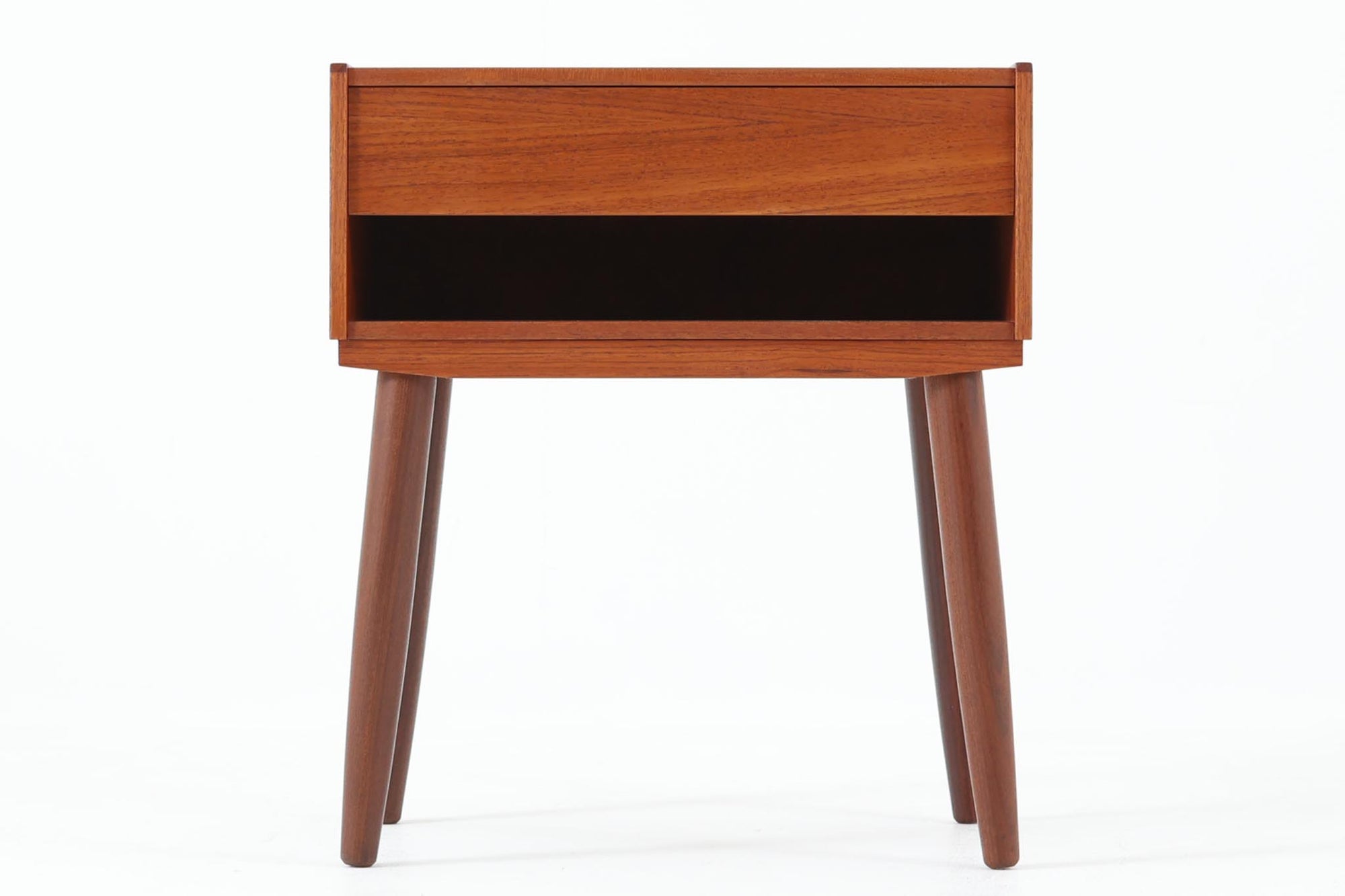デンマークで製造されたヴィンテージのサイドチェスト。温もりのあるチーク材を用いた本体に、先細りの丸脚を組み合わせた軽やかな佇まいが魅力です。引き出し1杯に加え、下部にはオープンスペースを備えており、リモコンや文庫本などをすぐに取り出せる実用的な構造。天板や側面にはすっきりとした面取りが施され、シンプルなデザインの中に丁寧な仕事が感じられます。北欧らしいあたたかみと実用性を兼ね備えた一台。ベッドサイドはもちろん、リビングや玄関先など、暮らしのさまざまな場面で活躍します。