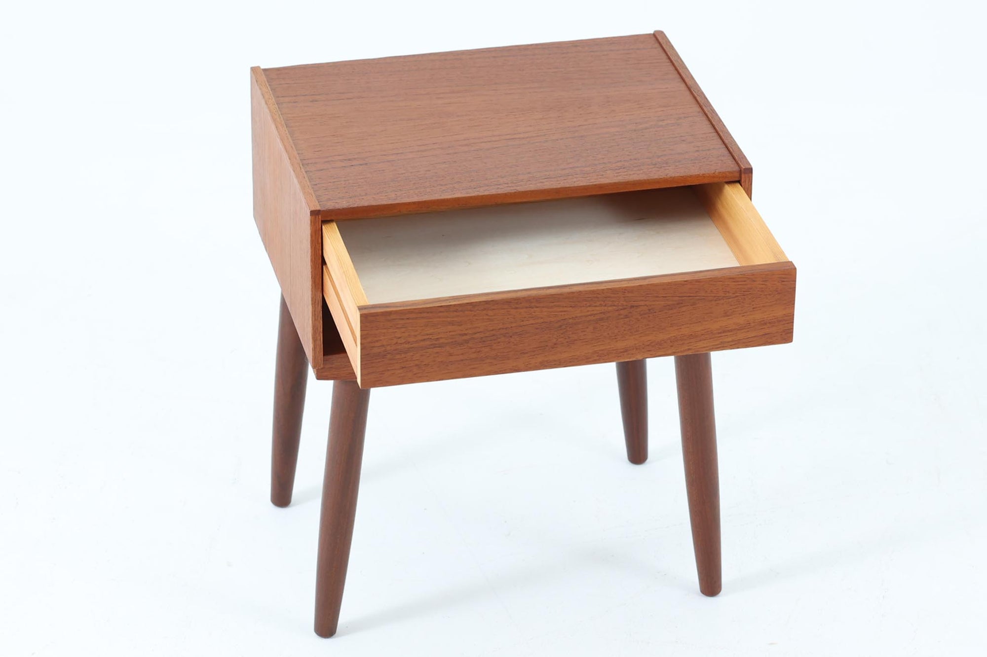 デンマークで製造されたヴィンテージのサイドチェスト。温もりのあるチーク材を用いた本体に、先細りの丸脚を組み合わせた軽やかな佇まいが魅力です。引き出し1杯に加え、下部にはオープンスペースを備えており、リモコンや文庫本などをすぐに取り出せる実用的な構造。天板や側面にはすっきりとした面取りが施され、シンプルなデザインの中に丁寧な仕事が感じられます。北欧らしいあたたかみと実用性を兼ね備えた一台。ベッドサイドはもちろん、リビングや玄関先など、暮らしのさまざまな場面で活躍します。