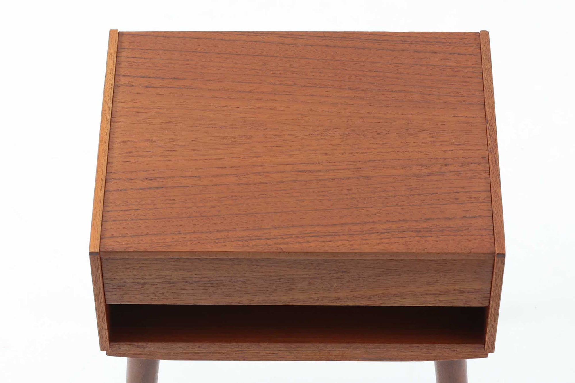 デンマークで製造されたヴィンテージのサイドチェスト。温もりのあるチーク材を用いた本体に、先細りの丸脚を組み合わせた軽やかな佇まいが魅力です。引き出し1杯に加え、下部にはオープンスペースを備えており、リモコンや文庫本などをすぐに取り出せる実用的な構造。天板や側面にはすっきりとした面取りが施され、シンプルなデザインの中に丁寧な仕事が感じられます。北欧らしいあたたかみと実用性を兼ね備えた一台。ベッドサイドはもちろん、リビングや玄関先など、暮らしのさまざまな場面で活躍します。