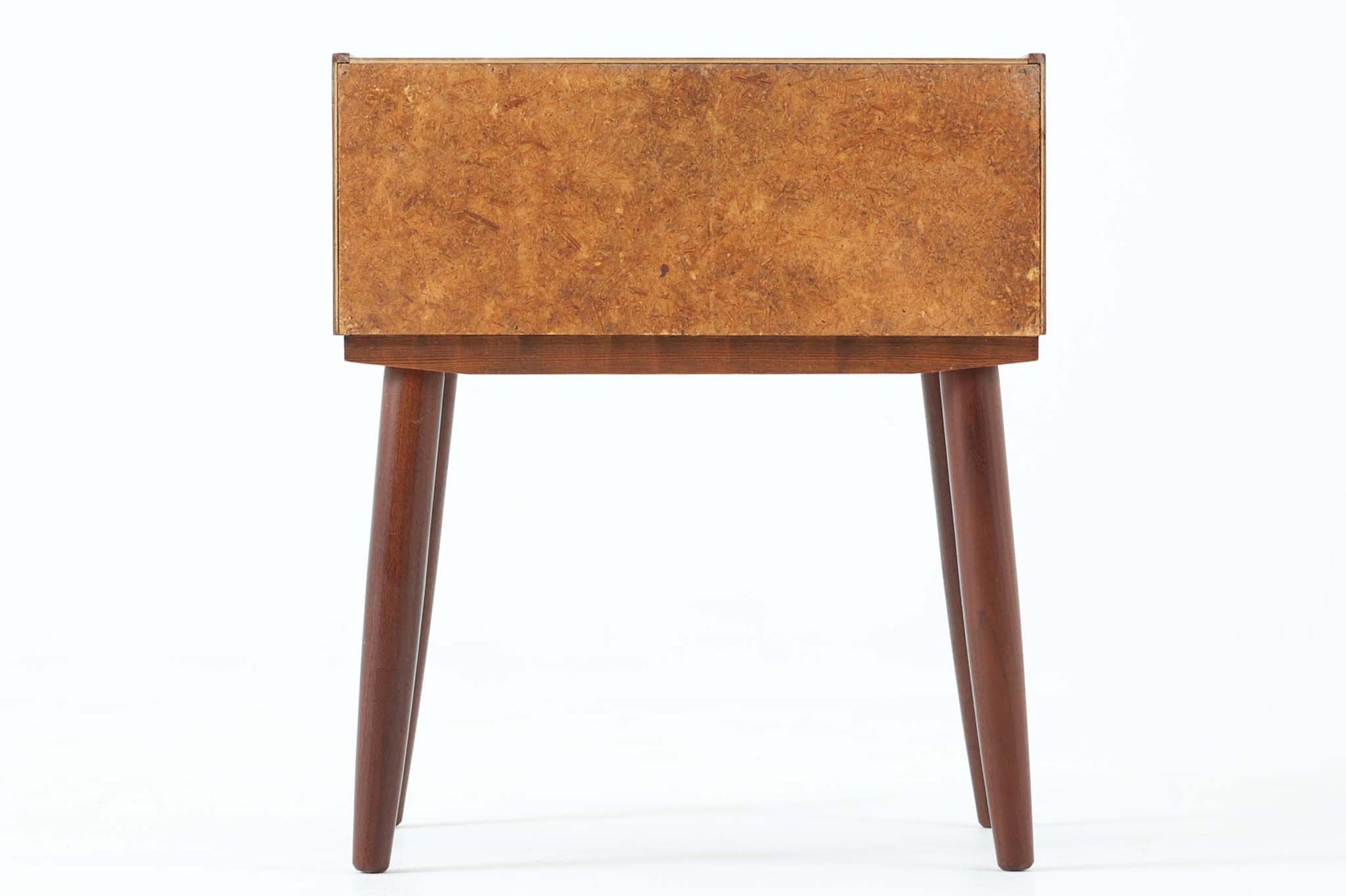 デンマークで製造されたヴィンテージのサイドチェスト。温もりのあるチーク材を用いた本体に、先細りの丸脚を組み合わせた軽やかな佇まいが魅力です。引き出し1杯に加え、下部にはオープンスペースを備えており、リモコンや文庫本などをすぐに取り出せる実用的な構造。天板や側面にはすっきりとした面取りが施され、シンプルなデザインの中に丁寧な仕事が感じられます。北欧らしいあたたかみと実用性を兼ね備えた一台。ベッドサイドはもちろん、リビングや玄関先など、暮らしのさまざまな場面で活躍します。