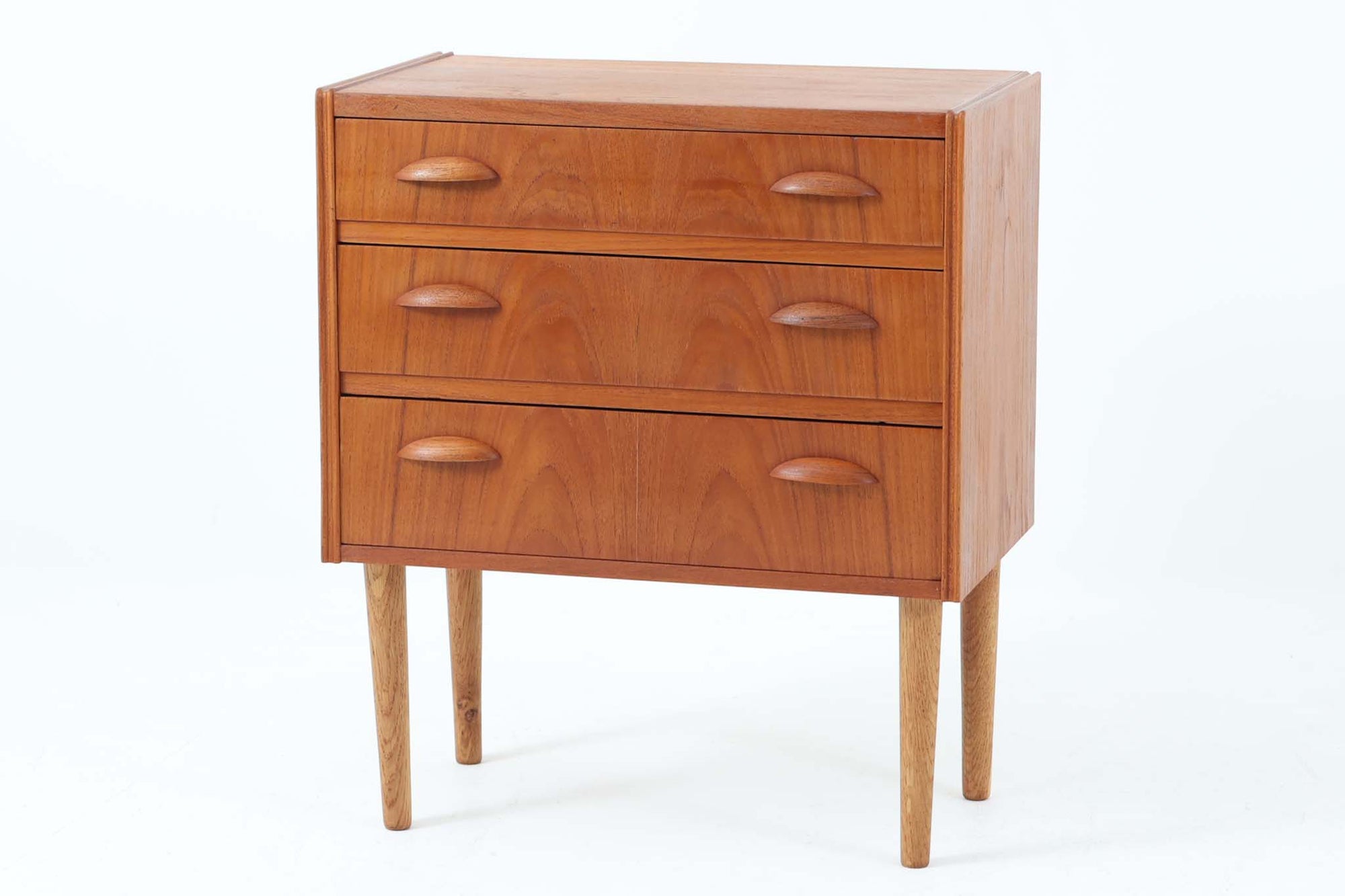 デンマークで製造されたヴィンテージの3段チェスト。本体には温かみのあるチーク材を使用し、脚部にはオーク材を採用した、北欧らしい素材のコントラストが魅力です。特徴的なのは、シャープな縁のデザイン。洗練されたラインがアクセントとなり、シンプルながらもスタイリッシュな印象を与えます。引き出しの取手は手に馴染む優れたグリップ感があり、実用性とデザイン性を兼ね備えた仕上がり。コンパクトなサイズながら収納力があり、ベッドサイドやリビング、玄関先など、さまざまなシーンで活躍します。脚に反りがあるためそれを考慮した価格に設定しております。