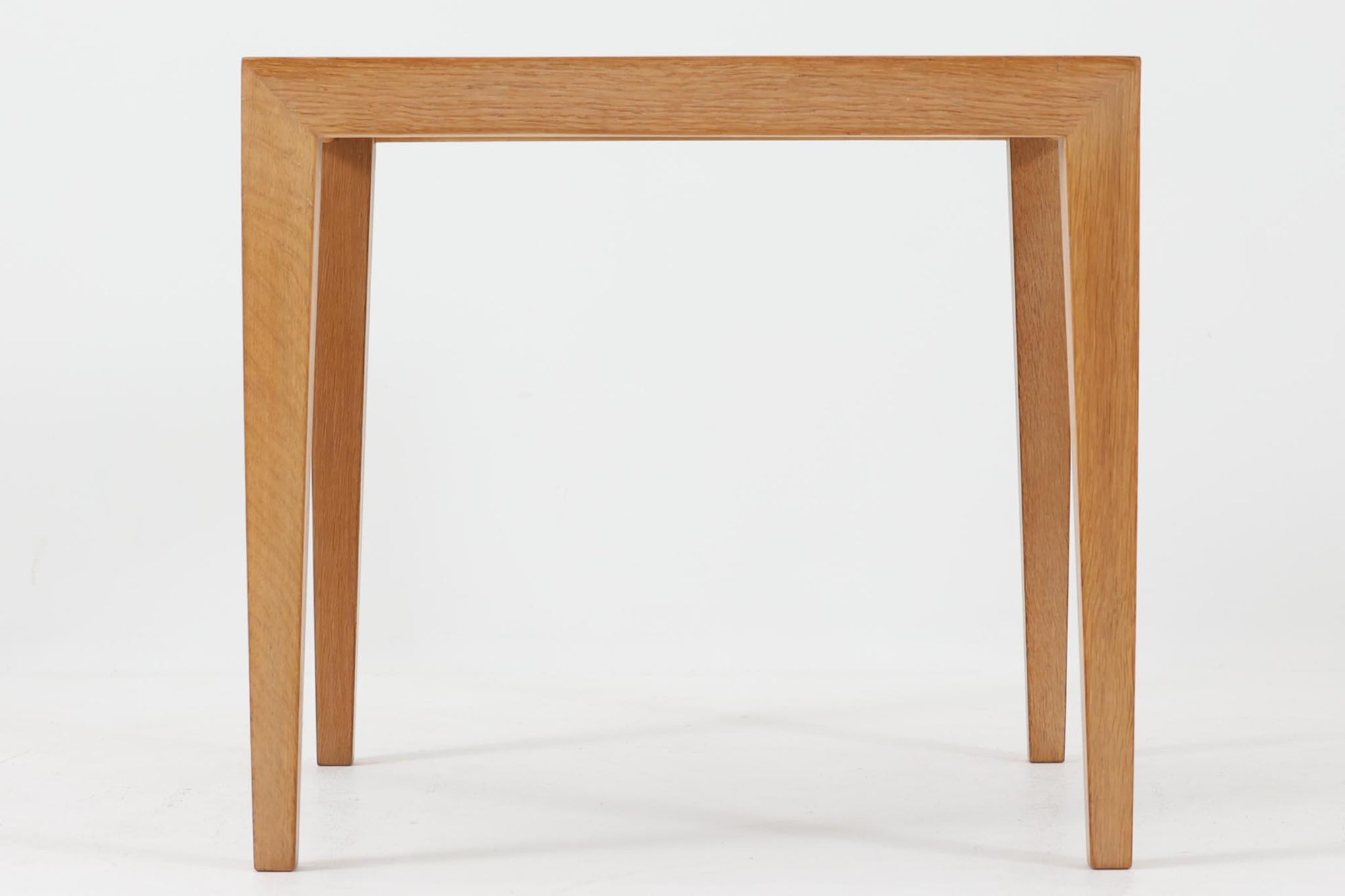 デンマークの家具デザイナー、Severin Hansen Jr.によってデザインされたビンテージのサイドテーブルです。製造はデンマークの名門家具メーカー「Haslev（ハスレヴ）」社。天板にはRoyal Copenhagen（ロイヤルコペンハーゲン）のアートタイルが贅沢にあしらわれています。タイルはNils Thorsson（ニルス・トーソン）が手掛けた人気の「BACA（バッカ）」シリーズ。象徴的なブルーとブラウンの色使いと、有機的かつ幾何学的なモチーフが印象的で、アートピースとしての存在感を放ちます。テーブル本体はオーク材を使用しており、Severin Hansen Jr.の特徴でもあるシャープなカットが施されたコーナーと、すっきりとしたテーパードレッグが、シンプルながら洗練された美しさを醸し出しています。ヴィンテージならではの深い味わいと、アート性・機能性を兼ね備えた一台。リビングやベッドサイドに、さりげなく上質な北欧デザインを取り入れてみてはいかがでしょうか。