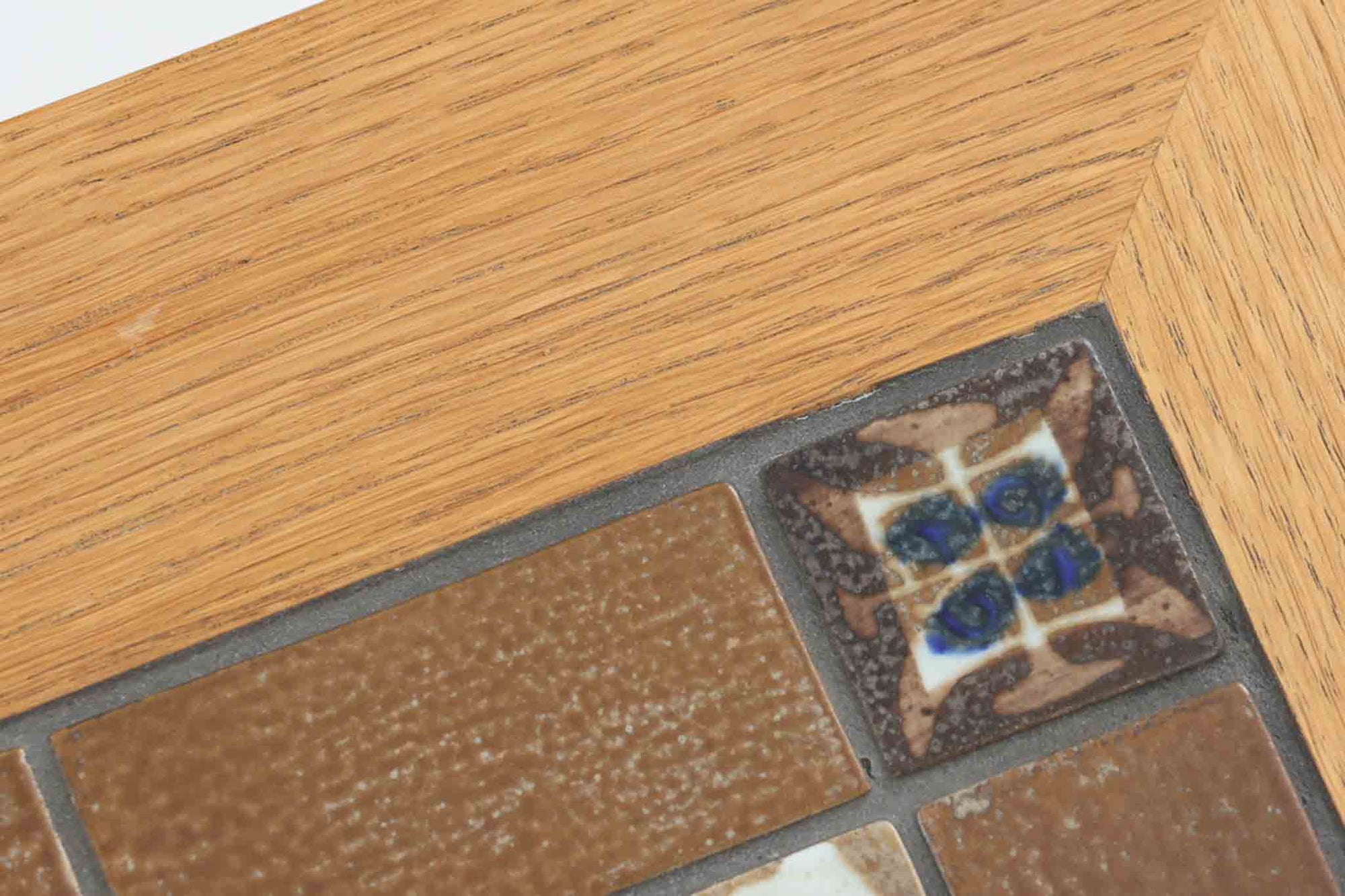 デンマークの家具デザイナー、Severin Hansen Jr.によってデザインされたビンテージのサイドテーブルです。製造はデンマークの名門家具メーカー「Haslev（ハスレヴ）」社。天板にはRoyal Copenhagen（ロイヤルコペンハーゲン）のアートタイルが贅沢にあしらわれています。タイルはNils Thorsson（ニルス・トーソン）が手掛けた人気の「BACA（バッカ）」シリーズ。象徴的なブルーとブラウンの色使いと、有機的かつ幾何学的なモチーフが印象的で、アートピースとしての存在感を放ちます。テーブル本体はオーク材を使用しており、Severin Hansen Jr.の特徴でもあるシャープなカットが施されたコーナーと、すっきりとしたテーパードレッグが、シンプルながら洗練された美しさを醸し出しています。ヴィンテージならではの深い味わいと、アート性・機能性を兼ね備えた一台。リビングやベッドサイドに、さりげなく上質な北欧デザインを取り入れてみてはいかがでしょうか。