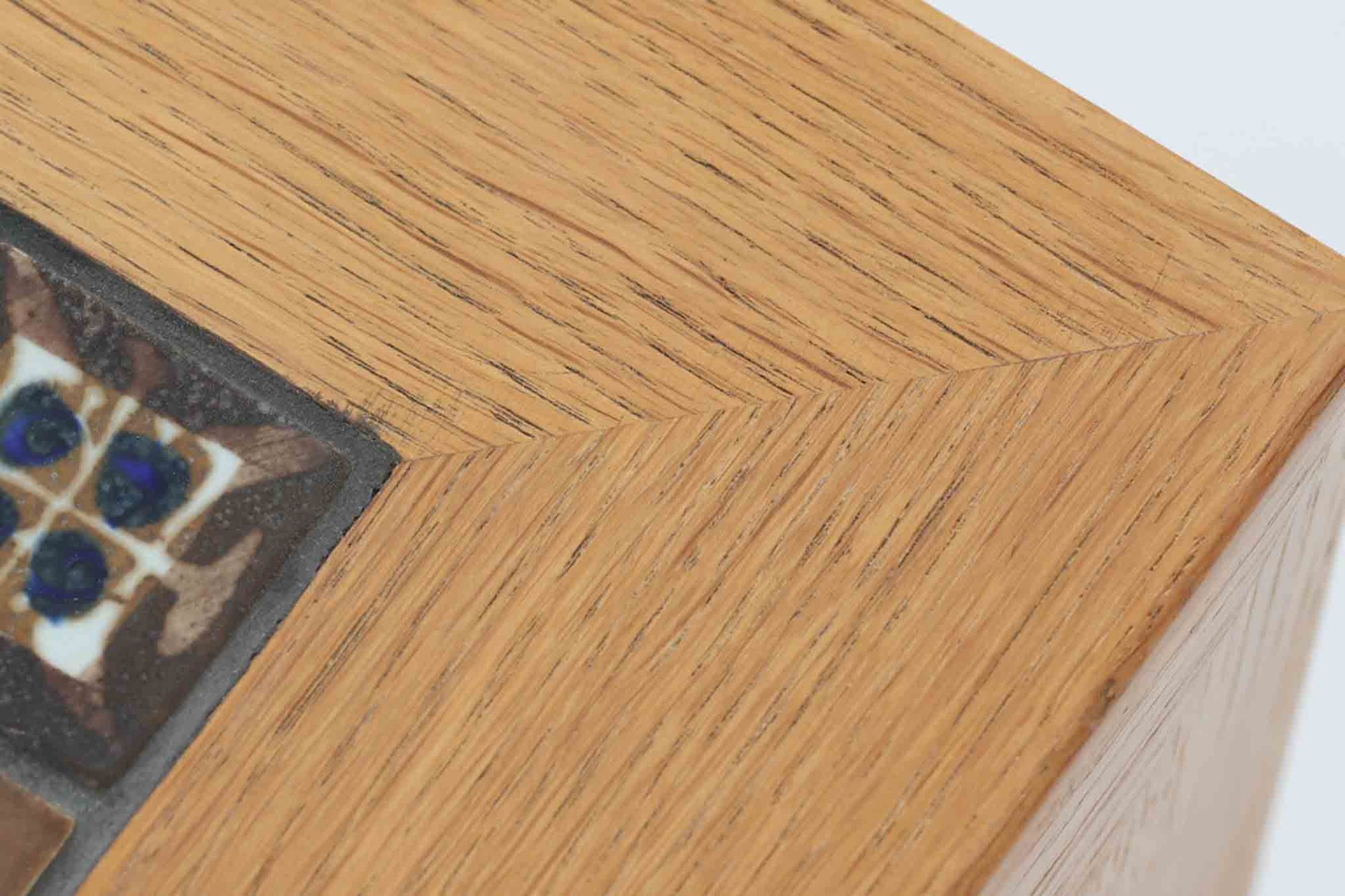 デンマークの家具デザイナー、Severin Hansen Jr.によってデザインされたビンテージのサイドテーブルです。製造はデンマークの名門家具メーカー「Haslev（ハスレヴ）」社。天板にはRoyal Copenhagen（ロイヤルコペンハーゲン）のアートタイルが贅沢にあしらわれています。タイルはNils Thorsson（ニルス・トーソン）が手掛けた人気の「BACA（バッカ）」シリーズ。象徴的なブルーとブラウンの色使いと、有機的かつ幾何学的なモチーフが印象的で、アートピースとしての存在感を放ちます。テーブル本体はオーク材を使用しており、Severin Hansen Jr.の特徴でもあるシャープなカットが施されたコーナーと、すっきりとしたテーパードレッグが、シンプルながら洗練された美しさを醸し出しています。ヴィンテージならではの深い味わいと、アート性・機能性を兼ね備えた一台。リビングやベッドサイドに、さりげなく上質な北欧デザインを取り入れてみてはいかがでしょうか。