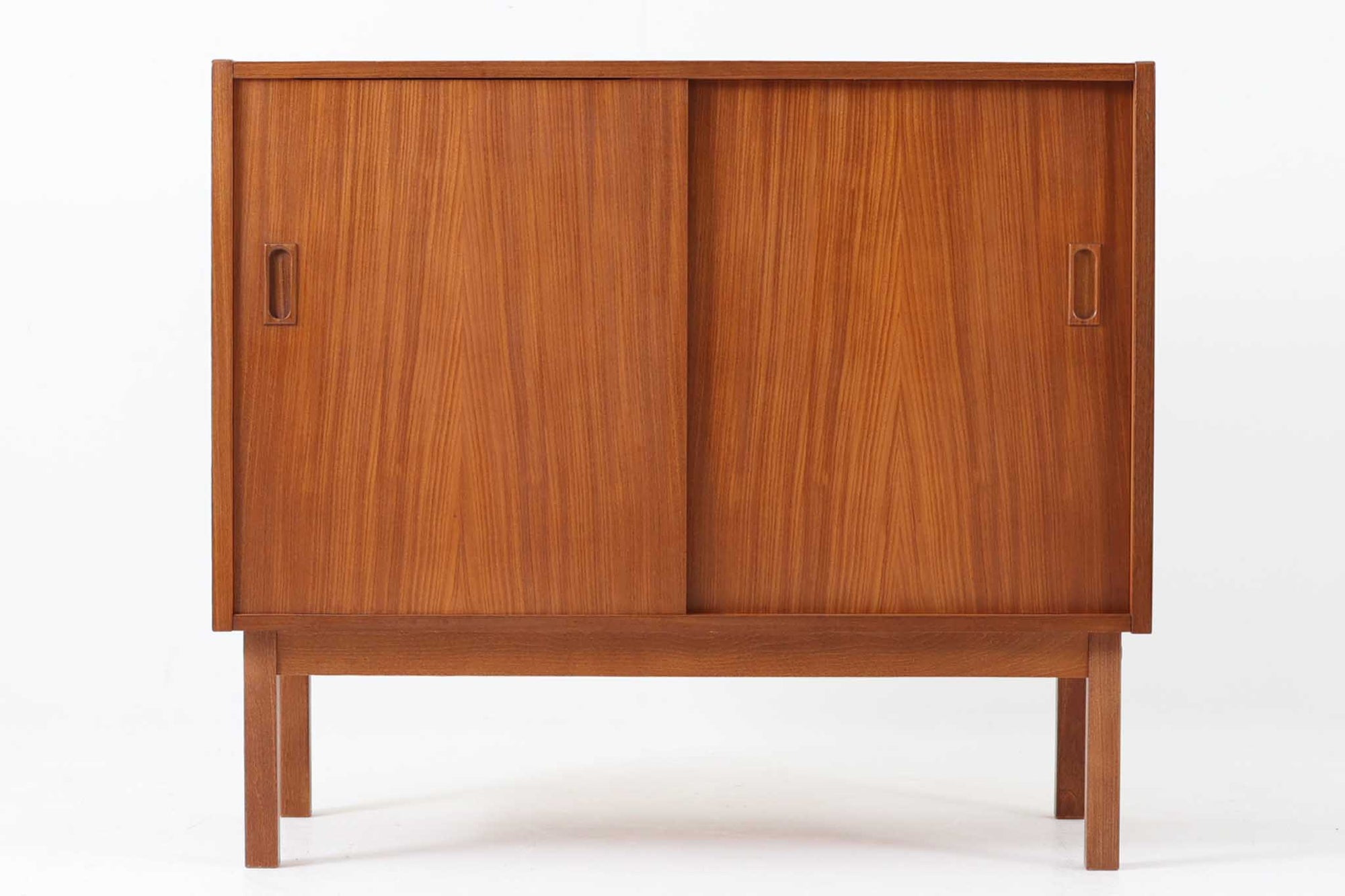 北欧ヴィンテージのチーク材ローボードです。幅81cmとコンパクトなサイズ感で、日本の住空間にも取り入れやすい一台。美しい木目が際立つスライド扉を備え、内部には可動式の棚板があり、収納力も十分です。洗練された直線的なデザインと、彫り込み取っ手の丁寧な仕上げが、北欧家具らしい実用性と美しさを兼ね備えています。高さも73cmと抑えられており、リビングボードやテレビ台としてはもちろん、玄関や寝室の収納家具としてもおすすめです。北欧デザインの温もりと機能美を感じられる一台です。