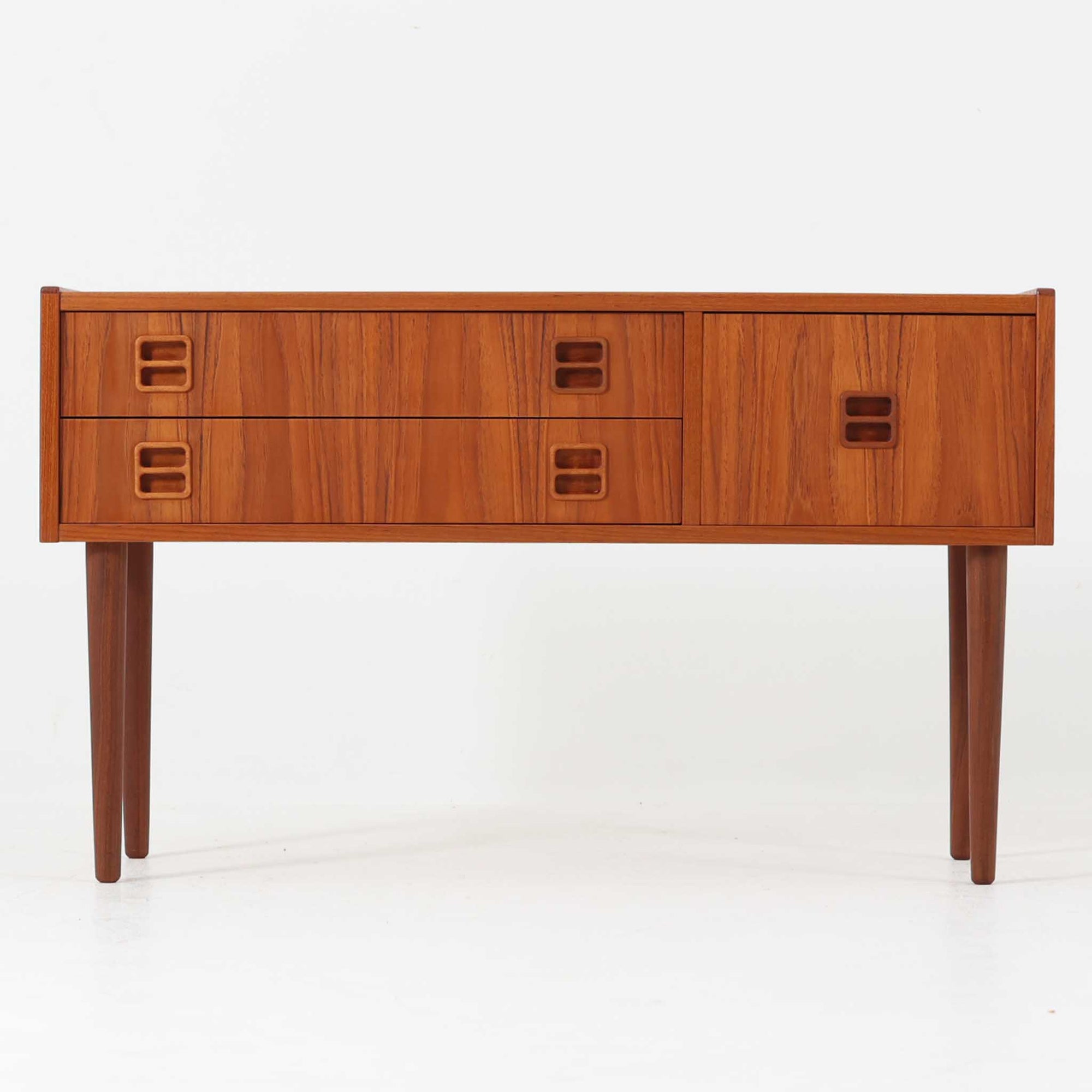 前板に施された彫り込み取手が印象的なこちらの多段チェストは、チーク材の美しい木目と引き締まったフォルムが特徴的で、幅89cmという程よいサイズ感に加え、3杯の引き出しが異なる深さで構成されており、収納力と実用性の高い北欧ビンテージ家具です。細身の脚部が全体を軽やかに見せ、玄関先やリビングのサイド収納としても活躍します。