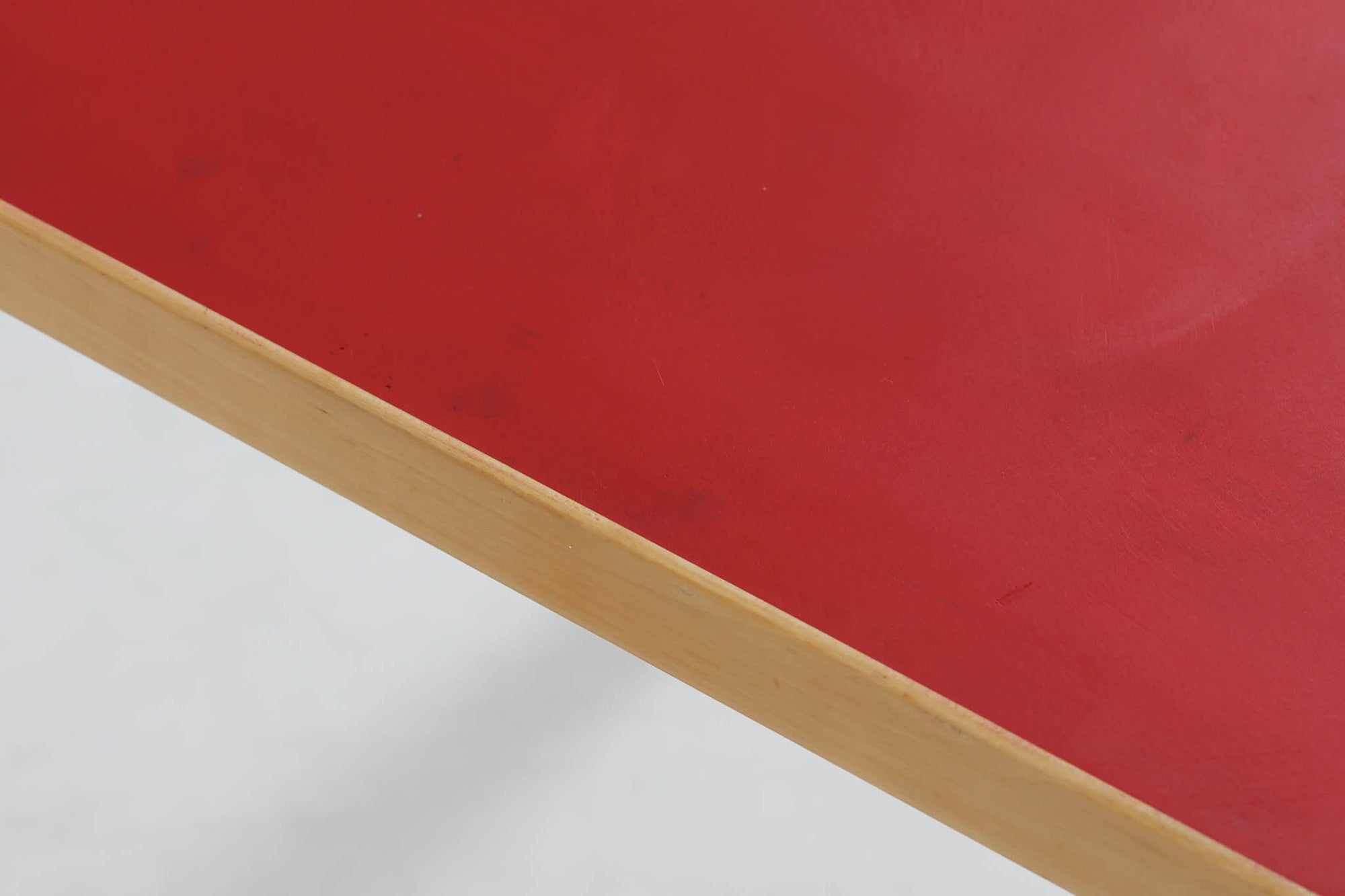 Artek社による、Alvar Aaltoデザインの幅120cmのダイニングテーブル。1970～1980年代に製造されたと考えられるヴィンテージ品です。Aaltoらしい流れるような曲線と、機能美を兼ね備えたデザインが特徴的。天板にはリノリウムが施されており、落ち着いたマットな質感と耐久性を備えています。温かみのあるバーチ材のフレームと、鮮やかなレッドの天板が美しいコントラストを生み出し、空間に独特の存在感を与えます。シンプルでありながら洗練された佇まいは、北欧デザインの魅力を存分に感じさせる一台です。