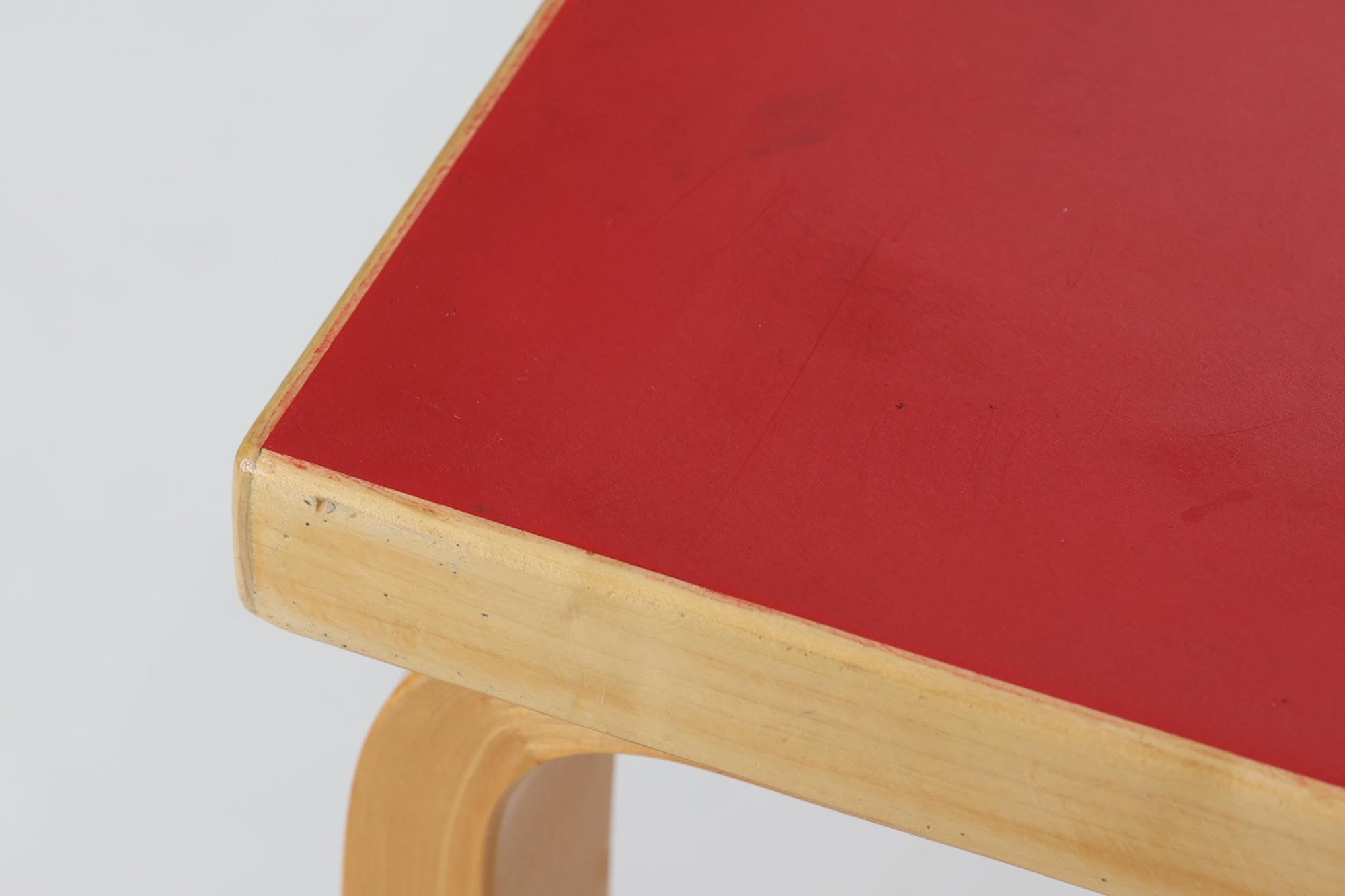 Artek社による、Alvar Aaltoデザインの幅120cmのダイニングテーブル。1970～1980年代に製造されたと考えられるヴィンテージ品です。Aaltoらしい流れるような曲線と、機能美を兼ね備えたデザインが特徴的。天板にはリノリウムが施されており、落ち着いたマットな質感と耐久性を備えています。温かみのあるバーチ材のフレームと、鮮やかなレッドの天板が美しいコントラストを生み出し、空間に独特の存在感を与えます。シンプルでありながら洗練された佇まいは、北欧デザインの魅力を存分に感じさせる一台です。