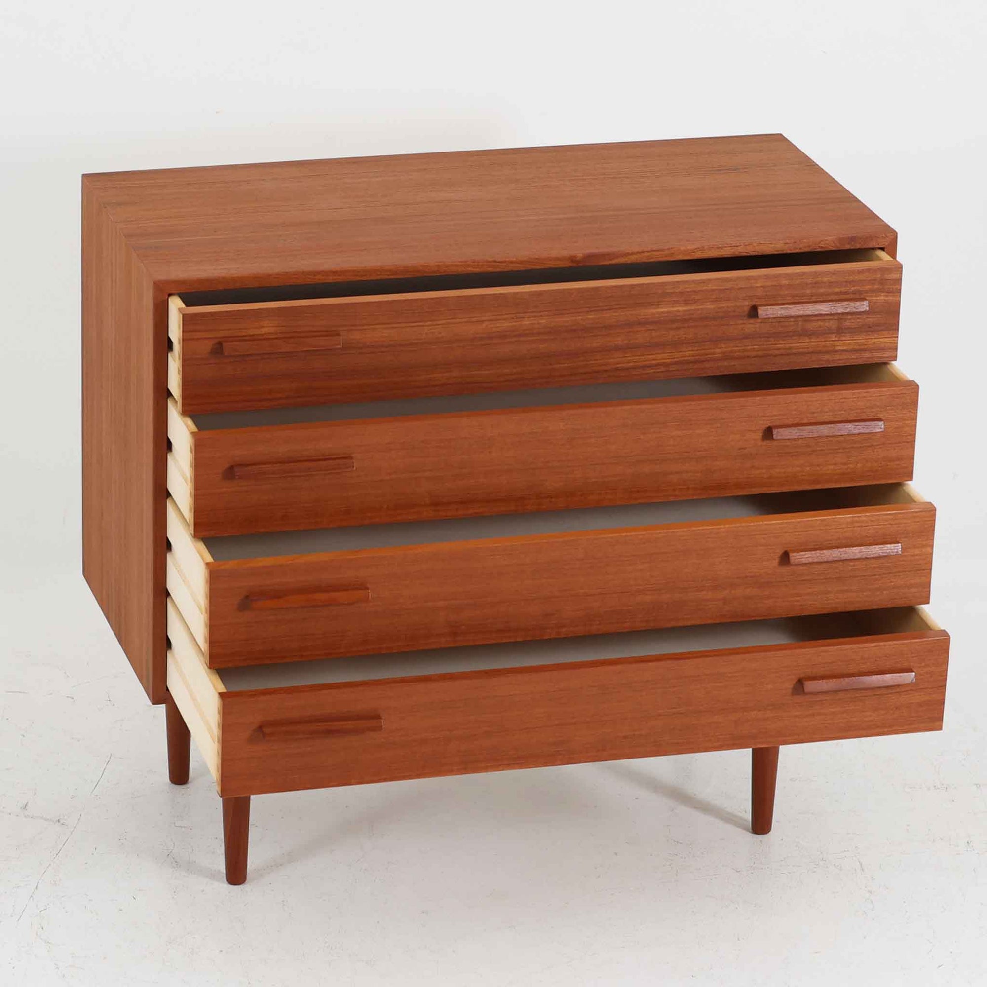 Kai Kristiansen（カイ・クリスチャンセン）によるデザインで、Feldballes Mobelfabrik社から製造された4段チェストです。端正なチーク材の木目と、すっきりとした直線構成が美しく調和し、北欧デザインらしい静かな上質さを感じさせます。細身のテーパー脚が軽やかな印象を与えつつ、引き出しの厚みや無垢材の取っ手が確かな存在感を放ちます。幅86cmの程よいサイズで、寝室やリビングの収納家具としても最適。経年によって深みを増したチーク材の艶が、ビンテージならではの味わいを引き立てています。