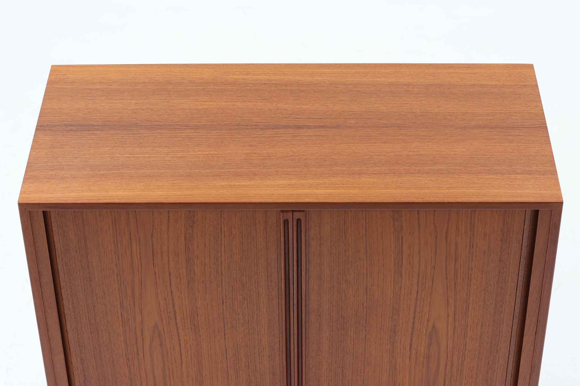 デンマークのデザイナー、Kai Kristiansen（カイ・クリスチャンセン）によってデザインされた、Fm furniture社製のビンテージキャビネットです。素材には上質なチーク材が用いられており、深みのある美しい木目とあたたかみのある色合いが魅力です。フロントには、機能性とデザイン性を兼ね備えた蛇腹扉が採用されており、開閉の動作そのものが楽しめる一台です。内部にはフェルトが敷かれた引き出し2段と収納スペースがあり、カトラリーや書類、小物の整理にも最適です。高さのある丸脚は、北欧家具らしい軽やかな印象を与えながらも、根元にかけてややふくらみを持たせた独特のフォルムとなっており、全体のデザイン性を高めています。コンパクトなサイズ感は空間を圧迫せず、リビングや玄関、書斎など様々なシーンに馴染みます。北欧デザインの美しさと実用性を兼ね備えたキャビネットです。