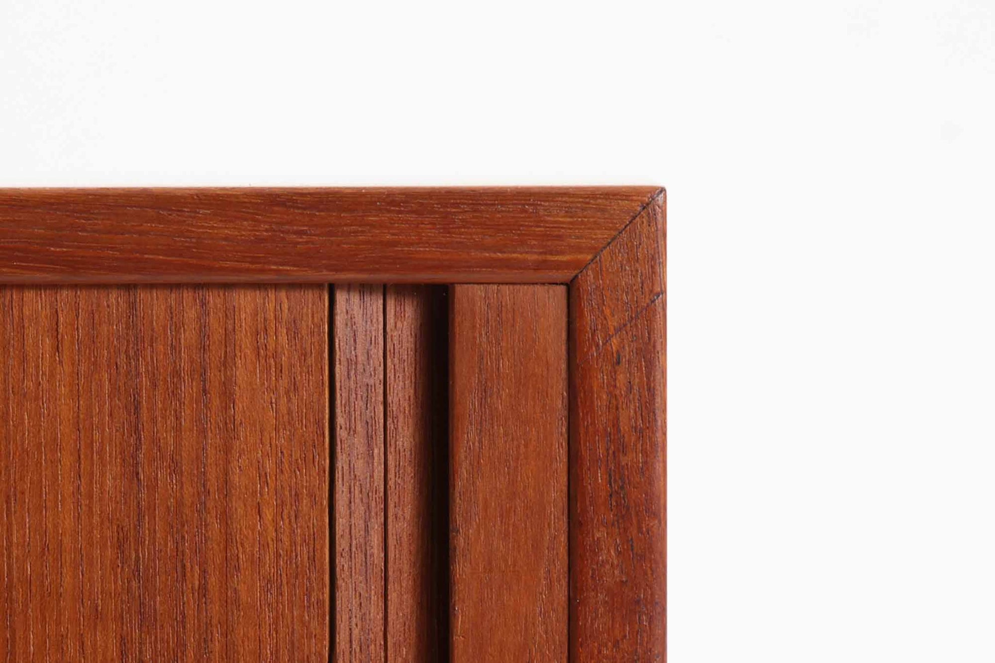 デンマークのデザイナー、Kai Kristiansen（カイ・クリスチャンセン）によってデザインされた、Fm furniture社製のビンテージキャビネットです。素材には上質なチーク材が用いられており、深みのある美しい木目とあたたかみのある色合いが魅力です。フロントには、機能性とデザイン性を兼ね備えた蛇腹扉が採用されており、開閉の動作そのものが楽しめる一台です。内部にはフェルトが敷かれた引き出し2段と収納スペースがあり、カトラリーや書類、小物の整理にも最適です。高さのある丸脚は、北欧家具らしい軽やかな印象を与えながらも、根元にかけてややふくらみを持たせた独特のフォルムとなっており、全体のデザイン性を高めています。コンパクトなサイズ感は空間を圧迫せず、リビングや玄関、書斎など様々なシーンに馴染みます。北欧デザインの美しさと実用性を兼ね備えたキャビネットです。