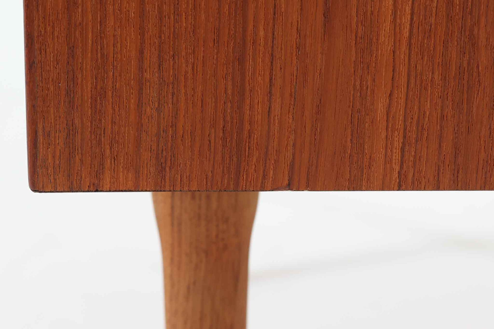 デンマークのデザイナー、Kai Kristiansen（カイ・クリスチャンセン）によってデザインされた、Fm furniture社製のビンテージキャビネットです。素材には上質なチーク材が用いられており、深みのある美しい木目とあたたかみのある色合いが魅力です。フロントには、機能性とデザイン性を兼ね備えた蛇腹扉が採用されており、開閉の動作そのものが楽しめる一台です。内部にはフェルトが敷かれた引き出し2段と収納スペースがあり、カトラリーや書類、小物の整理にも最適です。高さのある丸脚は、北欧家具らしい軽やかな印象を与えながらも、根元にかけてややふくらみを持たせた独特のフォルムとなっており、全体のデザイン性を高めています。コンパクトなサイズ感は空間を圧迫せず、リビングや玄関、書斎など様々なシーンに馴染みます。北欧デザインの美しさと実用性を兼ね備えたキャビネットです。