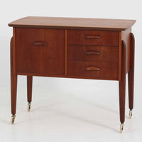 チーク材を使用したデンマーク製のソーイングテーブルです。丸みを帯びた脚部と有機的な取っ手のデザインが愛らしく、温かみのある木目が上品な印象を与えます。引き出し内には仕切りが設けられ、小物の整理にも便利。キャスター付きで移動もスムーズに行えます。ミシン台や裁縫用としてはもちろん、リビングでサイドテーブルや収納台としても活躍する汎用性の高い一台です。経年によるチークの深い色艶が、北欧ビンテージ家具ならではの趣を添えています。