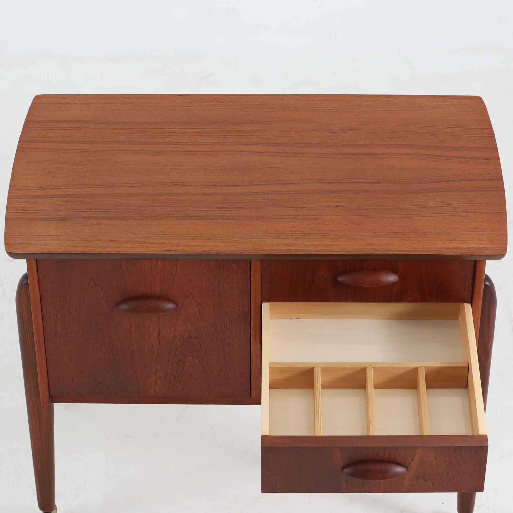 チーク材を使用したデンマーク製のソーイングテーブルです。丸みを帯びた脚部と有機的な取っ手のデザインが愛らしく、温かみのある木目が上品な印象を与えます。引き出し内には仕切りが設けられ、小物の整理にも便利。キャスター付きで移動もスムーズに行えます。ミシン台や裁縫用としてはもちろん、リビングでサイドテーブルや収納台としても活躍する汎用性の高い一台です。経年によるチークの深い色艶が、北欧ビンテージ家具ならではの趣を添えています。