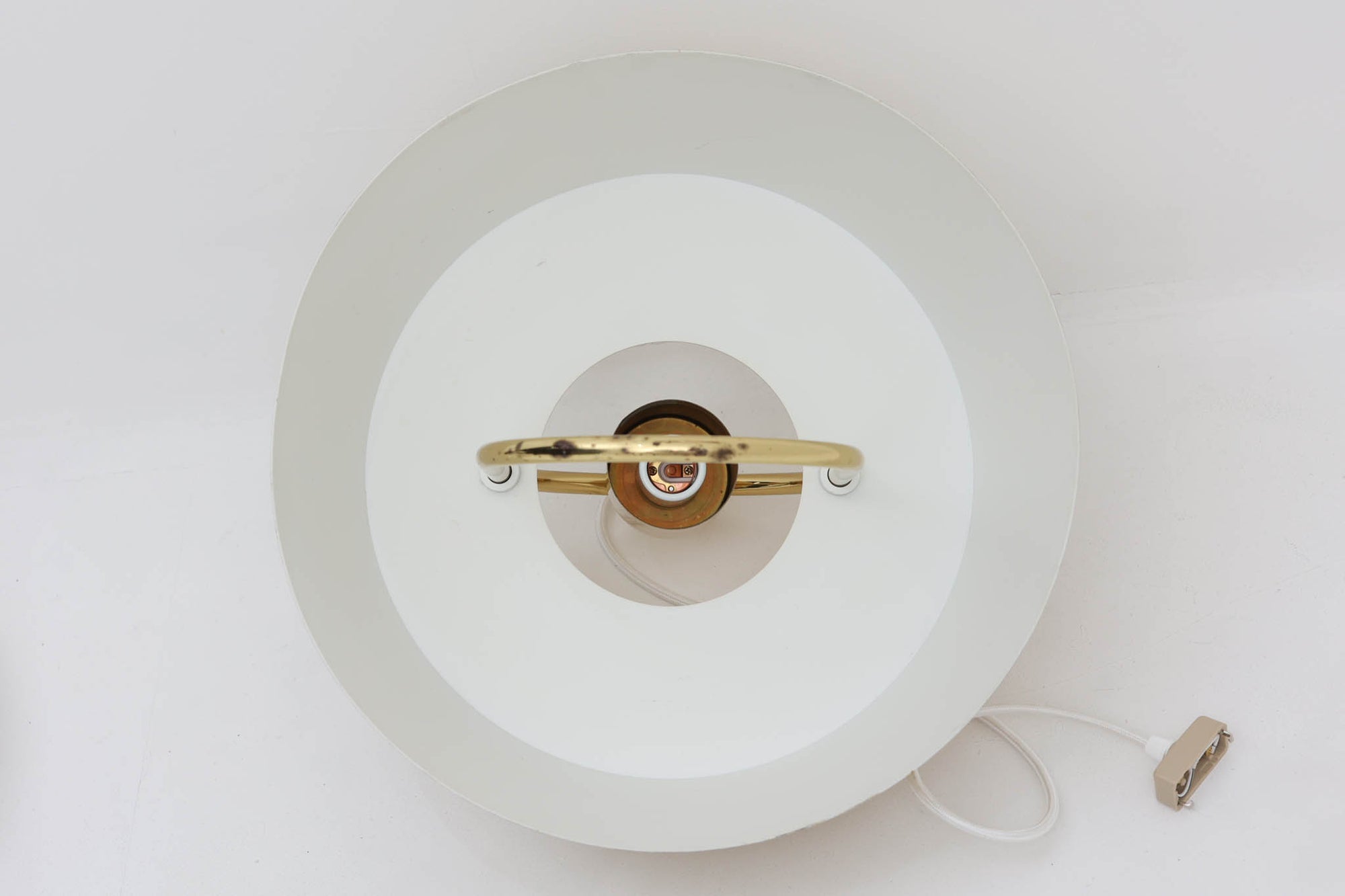 デンマークの照明ブランド、Fog &amp; morup（フォグ＆モーラップ）社によるペンダントライト「Hercules」。デザインは同社を代表するデザイナー、Jo Hammerborg（ヨー・ハーマボー）。直径41cmの存在感あるサイズに、上下を弧状に囲む真鍮製のアームが印象的な構造で、点灯時には下部のリングが光を受けて柔らかく浮かび上がります。外側はゴールドブラス、内側はホワイトで塗装されており、光の反射を美しく拡散させる仕様です。経年により一部にくすみや細かなキズが見られますが、全体としては美しい輝きを保っており、ビンテージならではの雰囲気を楽しめる一点です。E26口金のLED電球に対応し、現代の生活空間でも安心してご使用いただけます。北欧ミッドセンチュリーデザインの象徴的な一灯として、リビングやダイニングのアクセントにおすすめです。