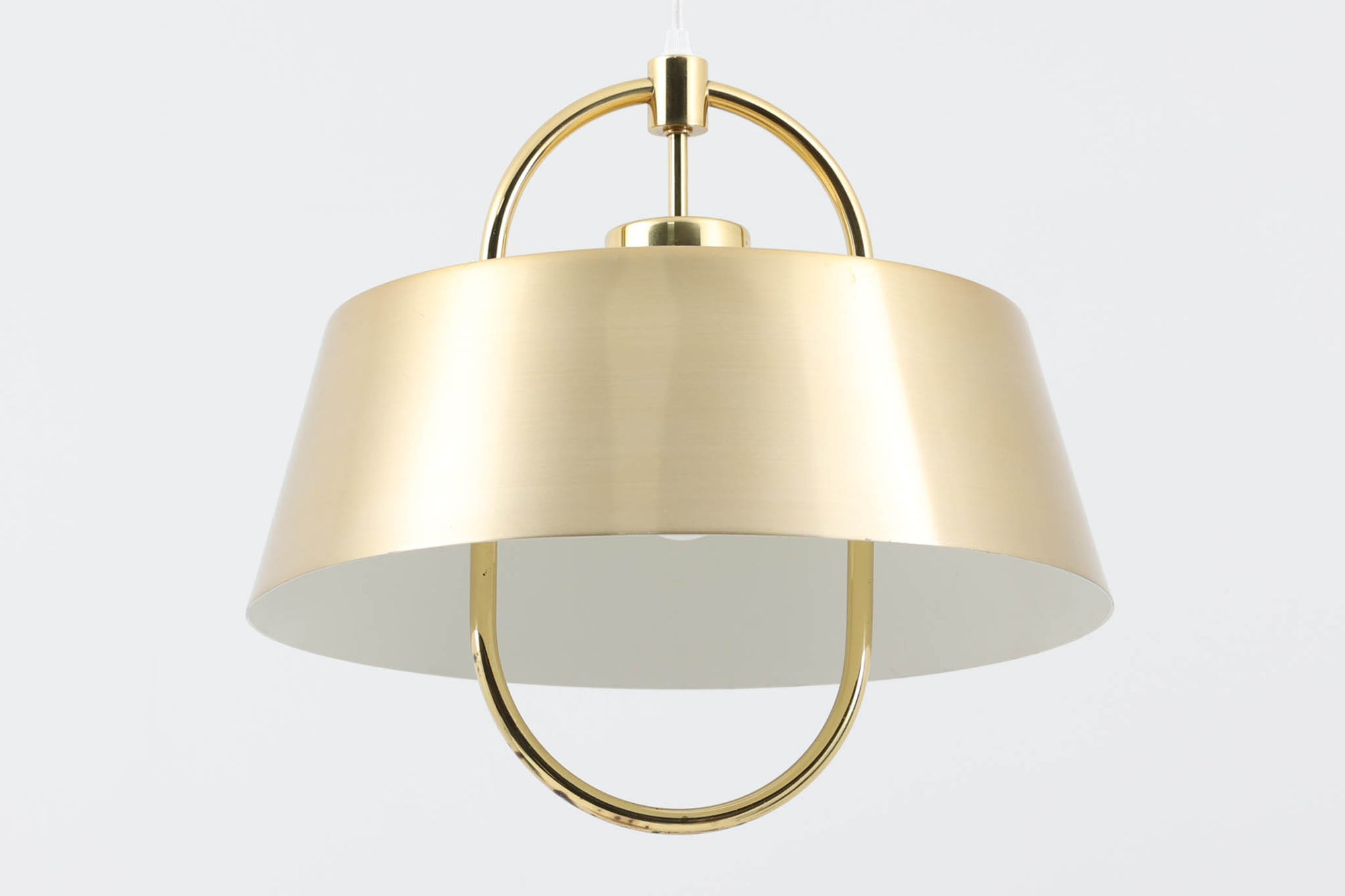 デンマークの照明ブランド、Fog &amp; morup（フォグ＆モーラップ）社によるペンダントライト「Hercules」。デザインは同社を代表するデザイナー、Jo Hammerborg（ヨー・ハーマボー）。直径41cmの存在感あるサイズに、上下を弧状に囲む真鍮製のアームが印象的な構造で、点灯時には下部のリングが光を受けて柔らかく浮かび上がります。外側はゴールドブラス、内側はホワイトで塗装されており、光の反射を美しく拡散させる仕様です。経年により一部にくすみや細かなキズが見られますが、全体としては美しい輝きを保っており、ビンテージならではの雰囲気を楽しめる一点です。E26口金のLED電球に対応し、現代の生活空間でも安心してご使用いただけます。北欧ミッドセンチュリーデザインの象徴的な一灯として、リビングやダイニングのアクセントにおすすめです。