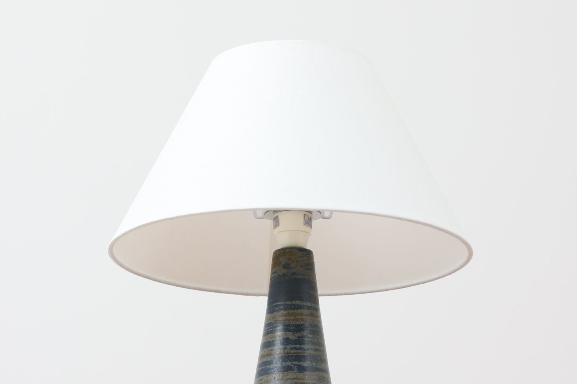 デンマーク・ボーンホルム島の名窯michael Andersen &amp; Sonによるテーブルランプ。八角形のシャープなフォルムと、マットな質感の釉薬のコントラストが美しい一点です。落ち着いたブルーグレーのトーンがインテリアに静かなアクセントを添えてくれます。高さは約50cmとやや大きめで、程よい存在感があり、サイドボードやコンソールの上などにもおすすめです。シェードは新品のリネン製。