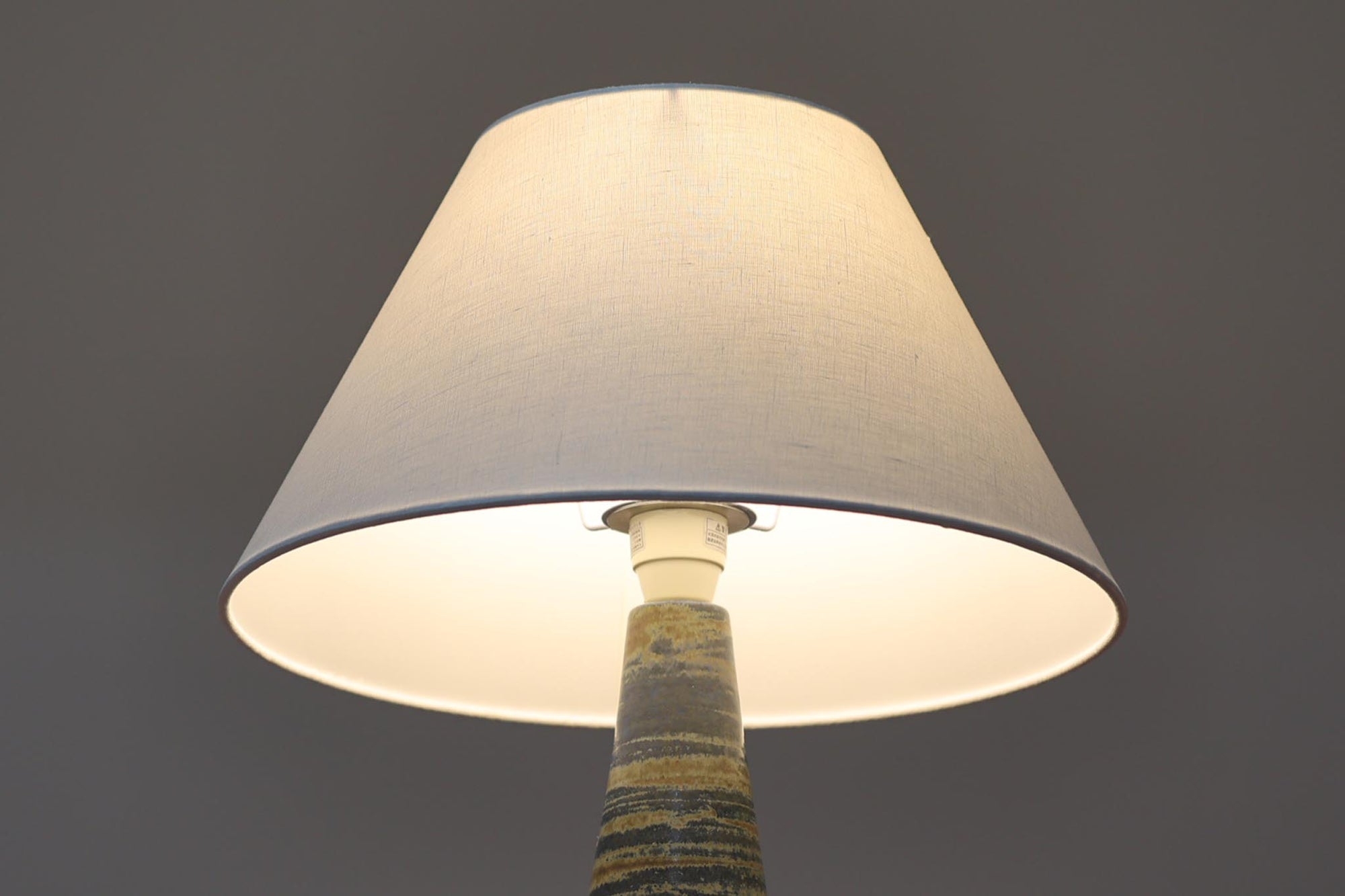 デンマーク・ボーンホルム島の名窯michael Andersen &amp; Sonによるテーブルランプ。八角形のシャープなフォルムと、マットな質感の釉薬のコントラストが美しい一点です。落ち着いたブルーグレーのトーンがインテリアに静かなアクセントを添えてくれます。高さは約50cmとやや大きめで、程よい存在感があり、サイドボードやコンソールの上などにもおすすめです。シェードは新品のリネン製。