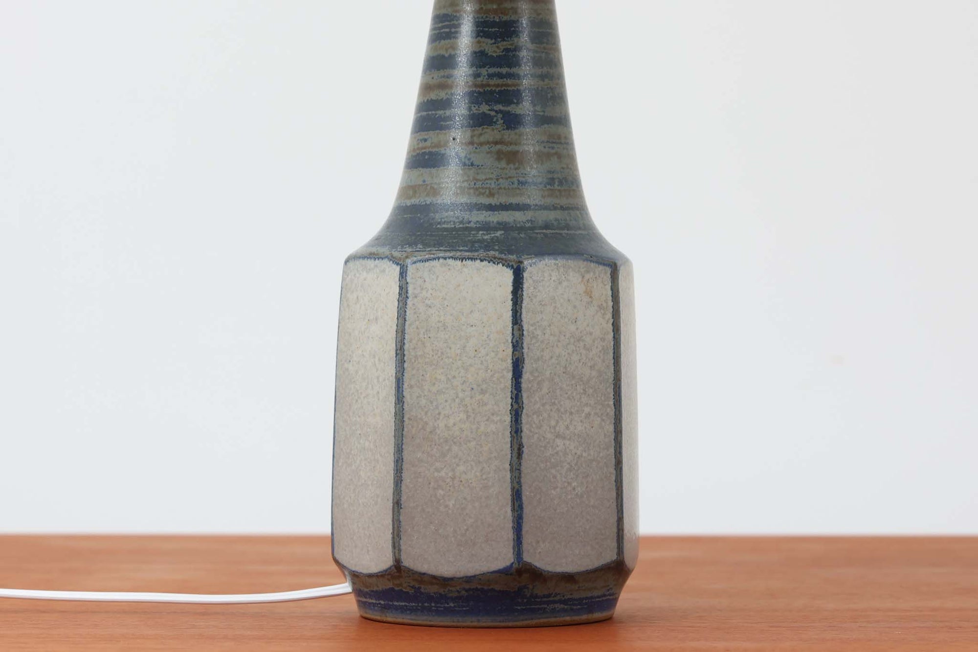 デンマーク・ボーンホルム島の名窯michael Andersen &amp; Sonによるテーブルランプ。八角形のシャープなフォルムと、マットな質感の釉薬のコントラストが美しい一点です。落ち着いたブルーグレーのトーンがインテリアに静かなアクセントを添えてくれます。高さは約50cmとやや大きめで、程よい存在感があり、サイドボードやコンソールの上などにもおすすめです。シェードは新品のリネン製。