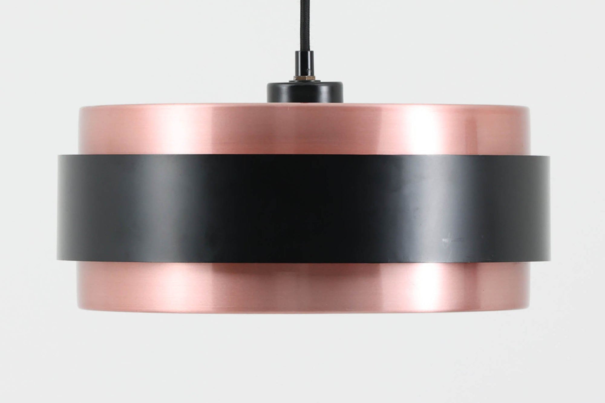 デンマークを代表する照明ブランドFog & morup（フォグ＆モーラップ）社によるペンダントライト「Saturn」。デザインは同社のチーフデザイナーとして数多くの名作を生み出したJo Hammerborg（ヨー・ハーマボー）によるもの。名前の通り土星をイメージさせる円盤状のシルエットが特徴で、銅色のボディにマットブラックのバンドがアクセントとなっています。点灯時にはアクリル製のディフューザーを通して柔らかな光が広がり、上部から漏れる光が本体に陰影を与える美しい構造です。直径は34cmと空間を圧迫しないサイズ感で、ダイニングや書斎、ベッドサイドなど多用途にお使いいただけます。ボトムカバーのガラスは付属しておりませんのでご了承ください。ビンテージならではの小傷や使用感が見られますが、全体的に良好なコンディションで、モダンインテリアに映える存在感のある一灯です。