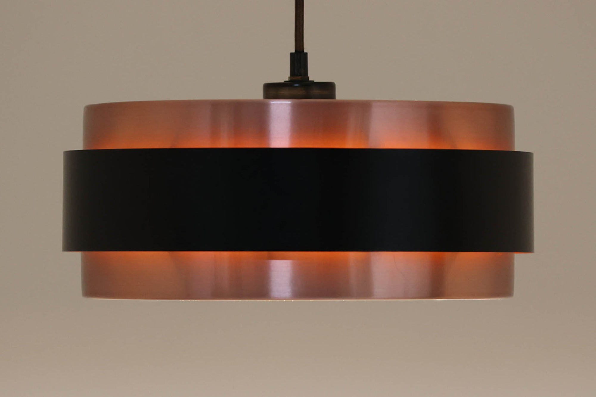 デンマークを代表する照明ブランドFog & morup（フォグ＆モーラップ）社によるペンダントライト「Saturn」。デザインは同社のチーフデザイナーとして数多くの名作を生み出したJo Hammerborg（ヨー・ハーマボー）によるもの。名前の通り土星をイメージさせる円盤状のシルエットが特徴で、銅色のボディにマットブラックのバンドがアクセントとなっています。点灯時にはアクリル製のディフューザーを通して柔らかな光が広がり、上部から漏れる光が本体に陰影を与える美しい構造です。直径は34cmと空間を圧迫しないサイズ感で、ダイニングや書斎、ベッドサイドなど多用途にお使いいただけます。ボトムカバーのガラスは付属しておりませんのでご了承ください。ビンテージならではの小傷や使用感が見られますが、全体的に良好なコンディションで、モダンインテリアに映える存在感のある一灯です。