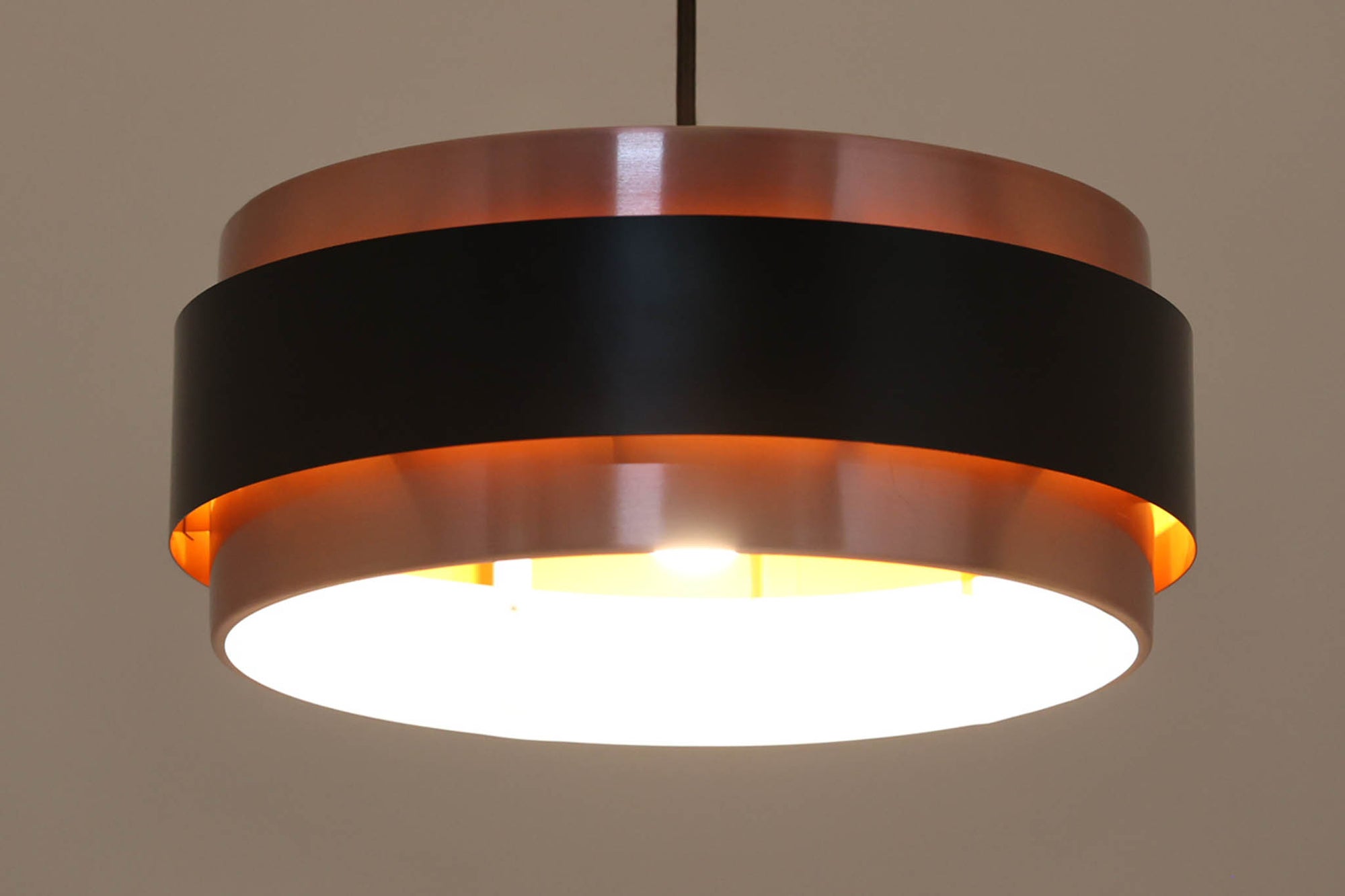 デンマークを代表する照明ブランドFog &amp; morup（フォグ＆モーラップ）社によるペンダントライト「Saturn」。デザインは同社のチーフデザイナーとして数多くの名作を生み出したJo Hammerborg（ヨー・ハーマボー）によるもの。名前の通り土星をイメージさせる円盤状のシルエットが特徴で、銅色のボディにマットブラックのバンドがアクセントとなっています。点灯時にはアクリル製のディフューザーを通して柔らかな光が広がり、上部から漏れる光が本体に陰影を与える美しい構造です。直径は34cmと空間を圧迫しないサイズ感で、ダイニングや書斎、ベッドサイドなど多用途にお使いいただけます。ボトムカバーのガラスは付属しておりませんのでご了承ください。ビンテージならではの小傷や使用感が見られますが、全体的に良好なコンディションで、モダンインテリアに映える存在感のある一灯です。