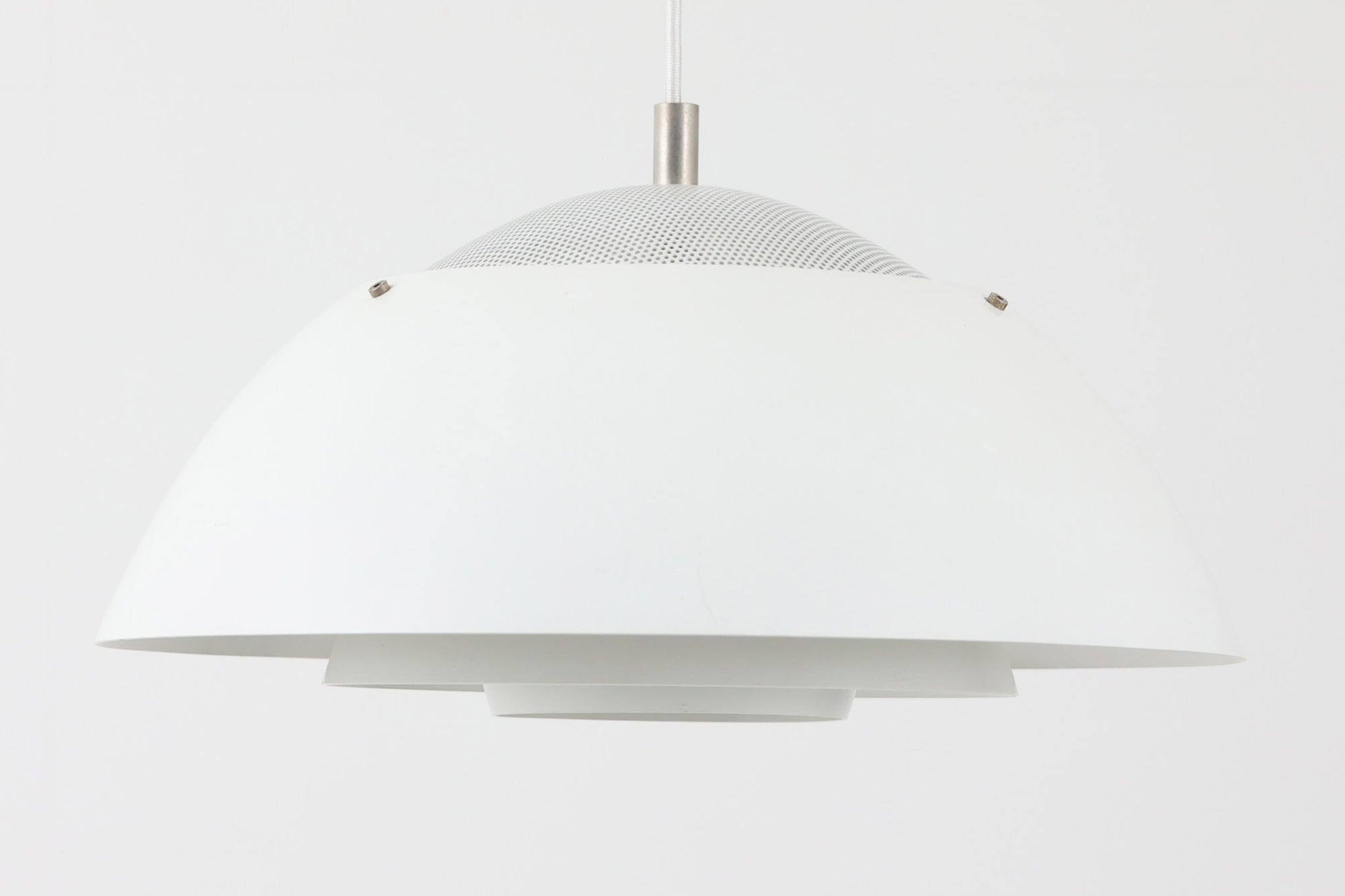 ​デンマークの照明メーカー**Nordisk Solar（ノルディック・ソーラー）**社で製造されたペンダントランプ“Safari（サファリ）”をご紹介します。​このランプは、1970年代にデンマークのデザイナー**Christian Hvidt**によってデザインされ、1981年に世界的に権威ある「iFプロダクトデザイン賞」を受賞しています。 ​デザインの特徴として、上部にはパンチングメタル製のトップディフューザーが配置されており、内部には角度の異なる2層のリフレクターを備えています。​これにより、光源が直接目に入らないグレアフリー構造となっており、柔らかな光が空間全体に穏やかに広がります。​北欧らしい機能美と造形美を兼ね備えたこの照明は、ダイニングやリビングはもちろん、商業空間のアクセントとしても最適です。一部には Hvidt & molgaard の関与を示唆する情報も見受けられますが、Safariランプは公式なデザイン史料や専門的な文献では Christian Hvidt による単独デザインとして紹介されています。本体サイズは直径47cmで、存在感のあるサイズながらも上品な佇まいを持つ一品です。