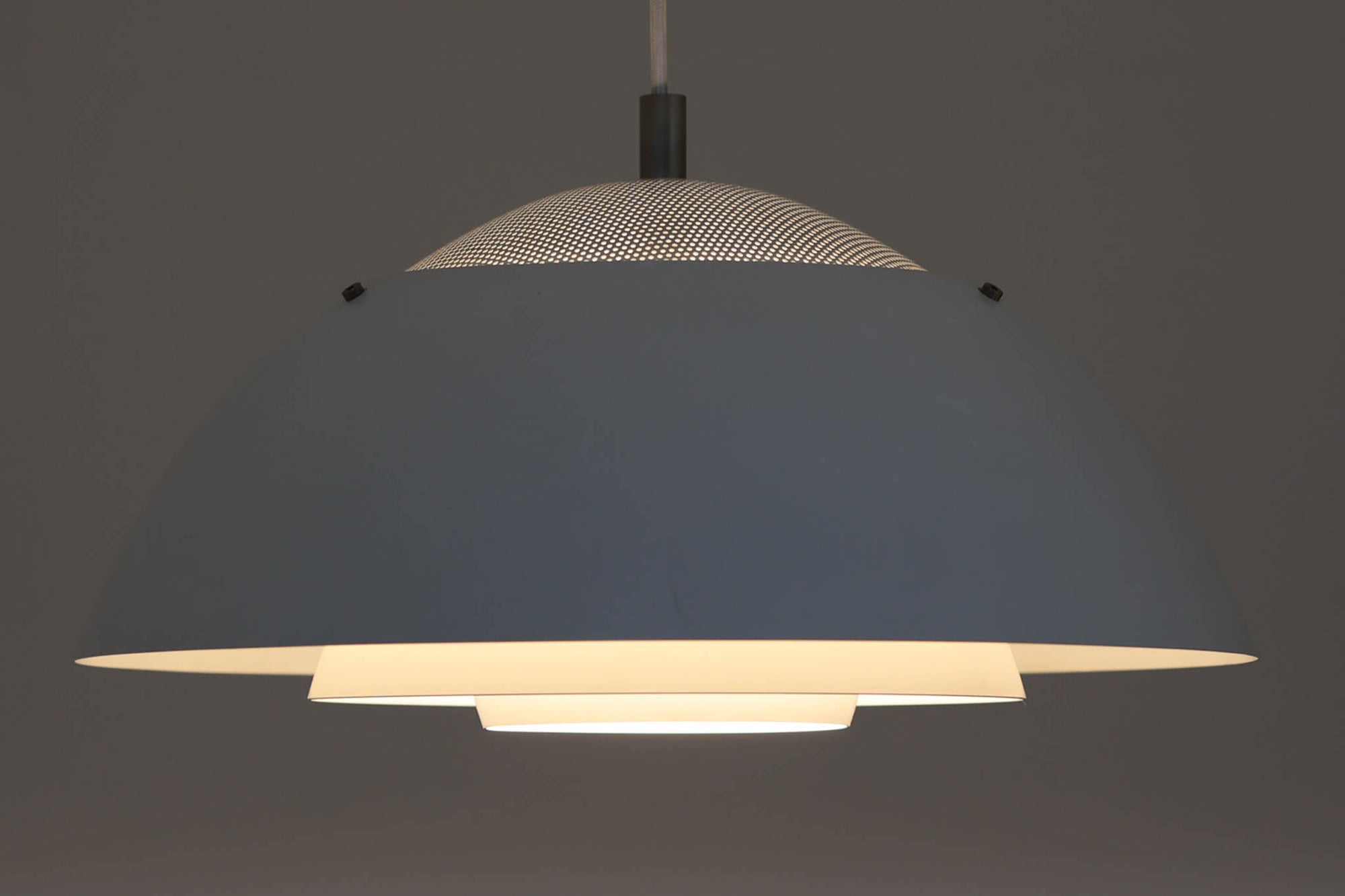 ​デンマークの照明メーカー**Nordisk Solar（ノルディック・ソーラー）**社で製造されたペンダントランプ“Safari（サファリ）”をご紹介します。​このランプは、1970年代にデンマークのデザイナー**Christian Hvidt**によってデザインされ、1981年に世界的に権威ある「iFプロダクトデザイン賞」を受賞しています。 ​デザインの特徴として、上部にはパンチングメタル製のトップディフューザーが配置されており、内部には角度の異なる2層のリフレクターを備えています。​これにより、光源が直接目に入らないグレアフリー構造となっており、柔らかな光が空間全体に穏やかに広がります。​北欧らしい機能美と造形美を兼ね備えたこの照明は、ダイニングやリビングはもちろん、商業空間のアクセントとしても最適です。一部には Hvidt & molgaard の関与を示唆する情報も見受けられますが、Safariランプは公式なデザイン史料や専門的な文献では Christian Hvidt による単独デザインとして紹介されています。本体サイズは直径47cmで、存在感のあるサイズながらも上品な佇まいを持つ一品です。