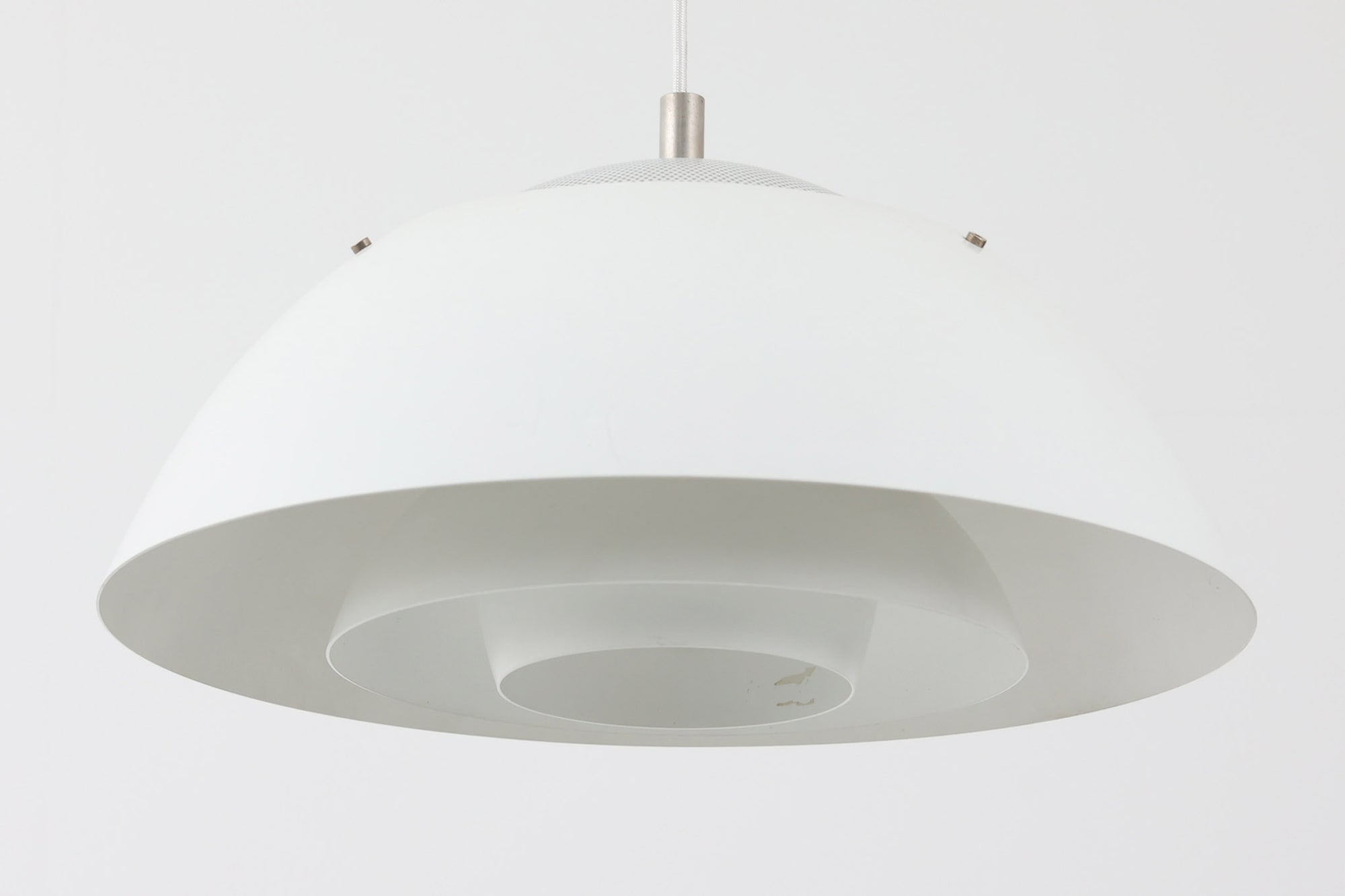 ​デンマークの照明メーカー**Nordisk Solar（ノルディック・ソーラー）**社で製造されたペンダントランプ“Safari（サファリ）”をご紹介します。​このランプは、1970年代にデンマークのデザイナー**Christian Hvidt**によってデザインされ、1981年に世界的に権威ある「iFプロダクトデザイン賞」を受賞しています。 ​デザインの特徴として、上部にはパンチングメタル製のトップディフューザーが配置されており、内部には角度の異なる2層のリフレクターを備えています。​これにより、光源が直接目に入らないグレアフリー構造となっており、柔らかな光が空間全体に穏やかに広がります。​北欧らしい機能美と造形美を兼ね備えたこの照明は、ダイニングやリビングはもちろん、商業空間のアクセントとしても最適です。一部には Hvidt &amp; molgaard の関与を示唆する情報も見受けられますが、Safariランプは公式なデザイン史料や専門的な文献では Christian Hvidt による単独デザインとして紹介されています。本体サイズは直径47cmで、存在感のあるサイズながらも上品な佇まいを持つ一品です。