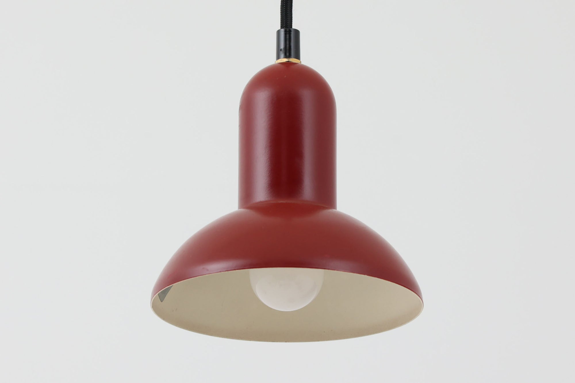 デンマークの老舗照明ブランドLYFA社による、Type 4784のビンテージペンダントライトです。丸みを帯びたチューブ状のトップから柔らかく広がるシェードへと続く滑らかなフォルムが特徴で、小ぶりながらも印象的な存在感を放ちます。直径14cmのコンパクトなサイズ感は、ダイニングやキッチンカウンター、玄関やトイレなどの小空間にも適しており、複数灯を並べても美しくまとまります。赤色の本体と、白く塗装された内側のコントラストが光を柔らかく反射させ、空間に温かみのある灯りをもたらします。シンプルでありながら北欧デザインらしい機能美が感じられる一品で、現行では手に入らない希少なビンテージアイテムとしておすすめです。