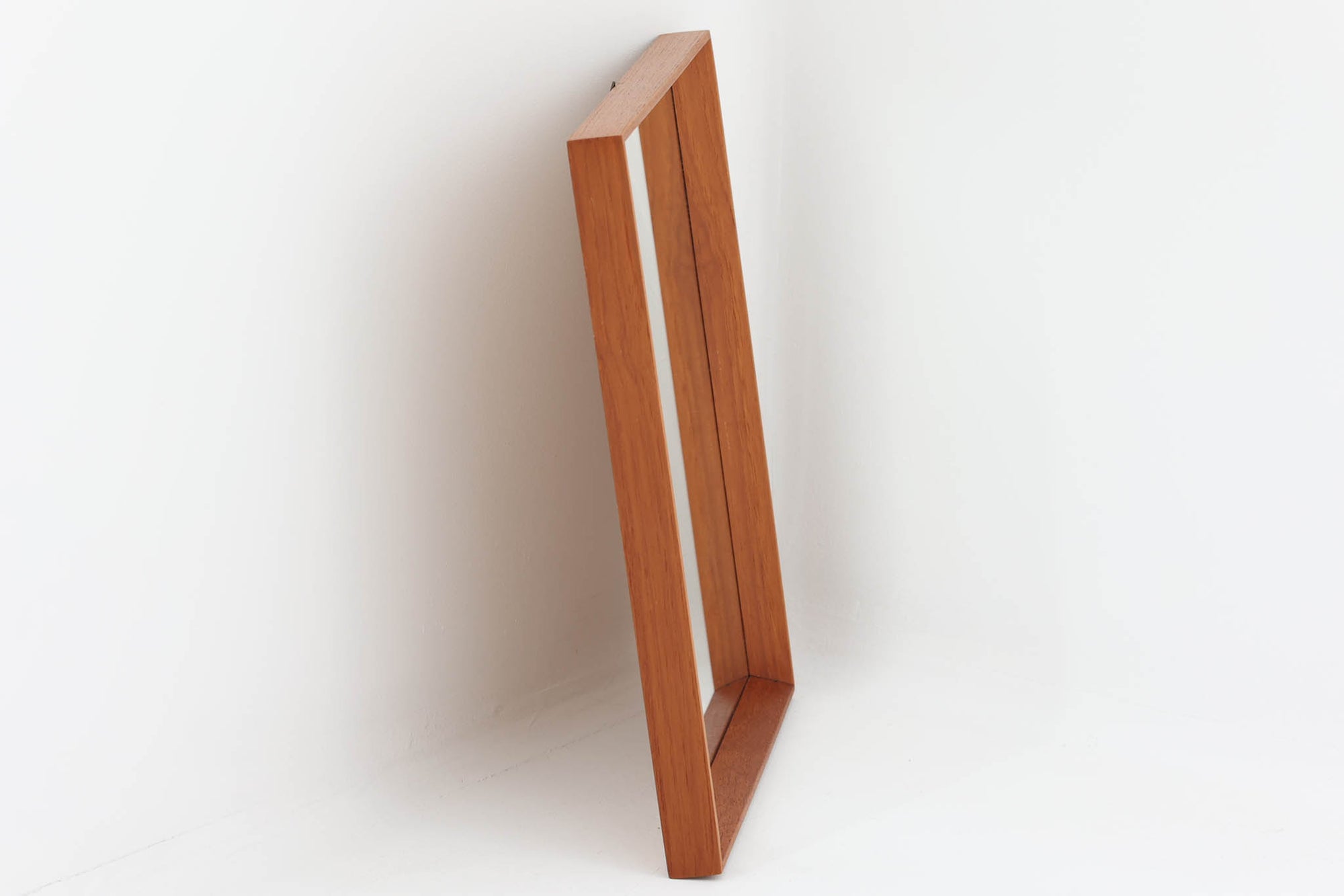 美しい木目が際立つチーク材で縁取られた壁掛け・立て掛け両用のミラーです。フレームの仕上げは細部にまで丁寧な加工が施され、シンプルながらも北欧ビンテージ家具特有の温もりと品格を感じさせるデザインに仕上がっています。高さ45cmのコンパクトなサイズ感は、玄関や洗面所、リビングなどさまざまな空間で取り入れやすく、空間に奥行きと明るさを加えるアイテムとして活躍します。日常使いはもちろん、装飾性も高くインテリアのアクセントとしてもおすすめです。