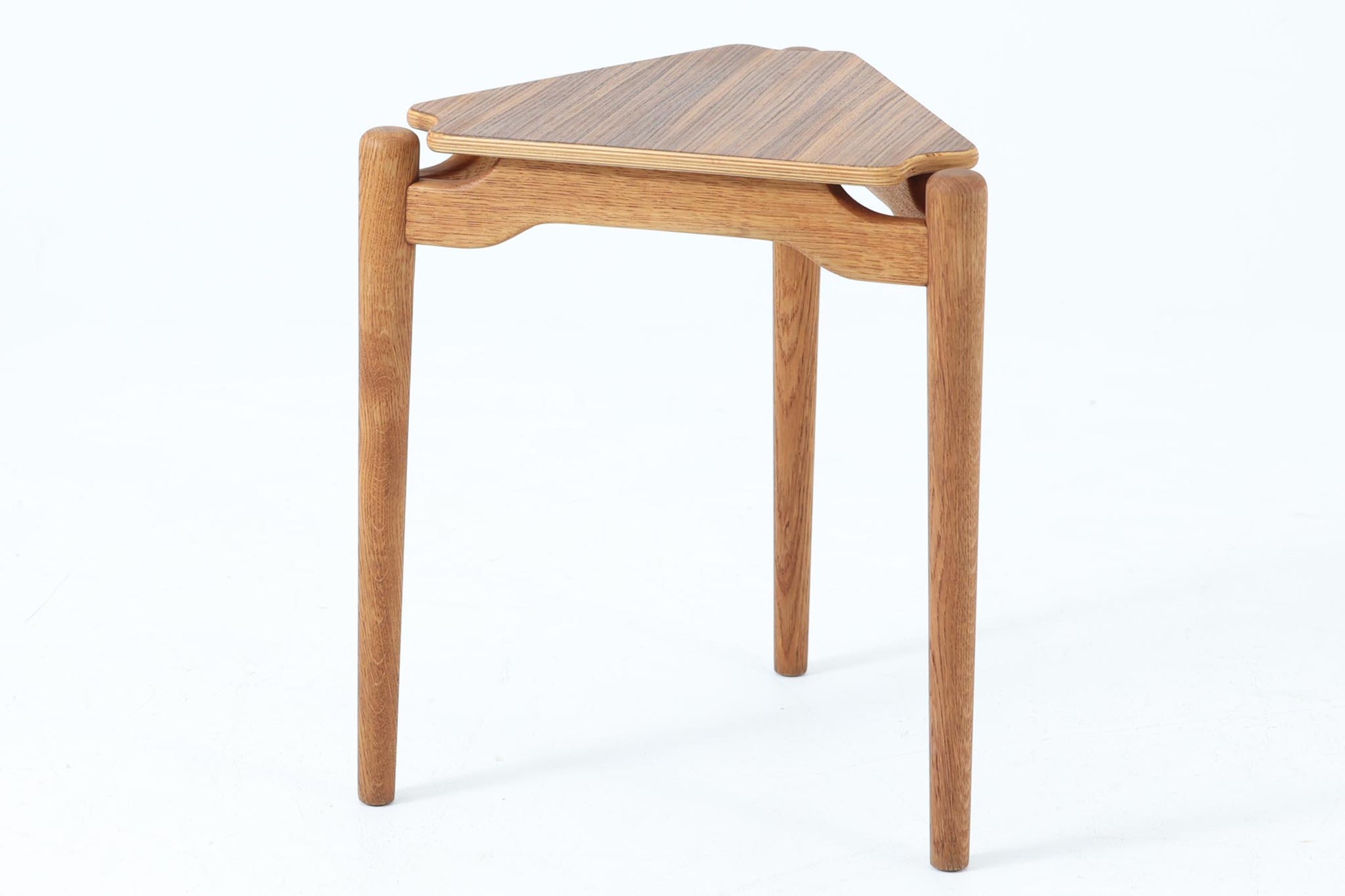 三角形の天板と3本の丸脚が特徴的なデンマーク製ビンテージサイドテーブルです。天板には美しい木目のチーク材を使用し、脚部には滑らかな質感のオーク材を採用。ユニークなフォルムながらもシンプルな佇まいで、空間に軽やかなアクセントを加えてくれます。花台としても活躍し、小さなスペースにも置きやすいサイズ感も魅力です。北欧デザインらしい丁寧な造りと温かみのある素材感をお楽しみいただけます。