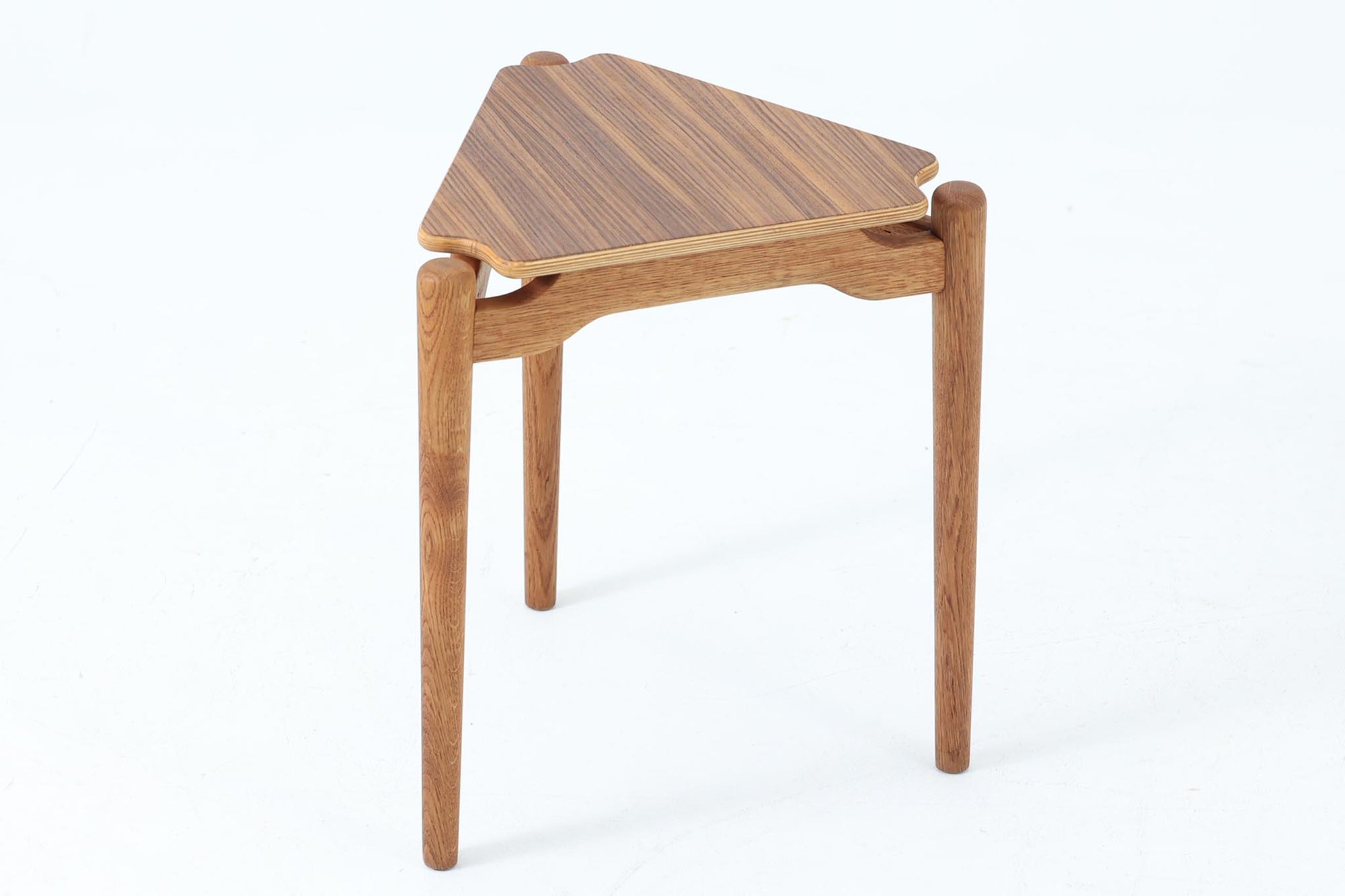 三角形の天板と3本の丸脚が特徴的なデンマーク製ビンテージサイドテーブルです。天板には美しい木目のチーク材を使用し、脚部には滑らかな質感のオーク材を採用。ユニークなフォルムながらもシンプルな佇まいで、空間に軽やかなアクセントを加えてくれます。花台としても活躍し、小さなスペースにも置きやすいサイズ感も魅力です。北欧デザインらしい丁寧な造りと温かみのある素材感をお楽しみいただけます。