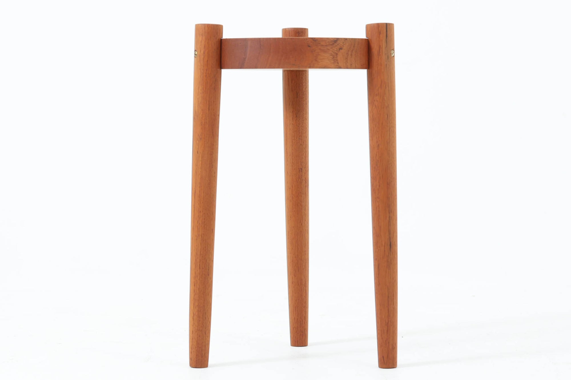 デンマーク製のビンテージ3本脚サイドテーブルです。天板・脚部ともにチーク無垢材を使用しており、木の質感を存分に楽しめる一品です。円形の天板に3本の丸脚を配したシンプルなデザインながら、脚の先端が天板を貫通して突き出した構造がアクセントとなり、クラフト感のある佇まいを演出しています。花台やソファ横のテーブルとしてなど、空間のポイントになる小家具としておすすめです。幅24cm×奥行24.5cmとコンパクトなサイズ感で、日本の住空間にも取り入れやすいアイテムです。