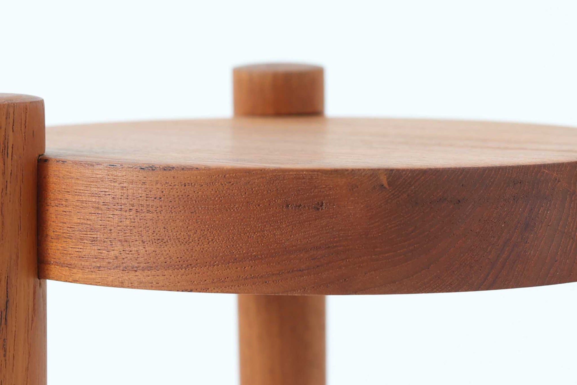 デンマーク製のビンテージ3本脚サイドテーブルです。天板・脚部ともにチーク無垢材を使用しており、木の質感を存分に楽しめる一品です。円形の天板に3本の丸脚を配したシンプルなデザインながら、脚の先端が天板を貫通して突き出した構造がアクセントとなり、クラフト感のある佇まいを演出しています。花台やソファ横のテーブルとしてなど、空間のポイントになる小家具としておすすめです。幅24cm×奥行24.5cmとコンパクトなサイズ感で、日本の住空間にも取り入れやすいアイテムです。