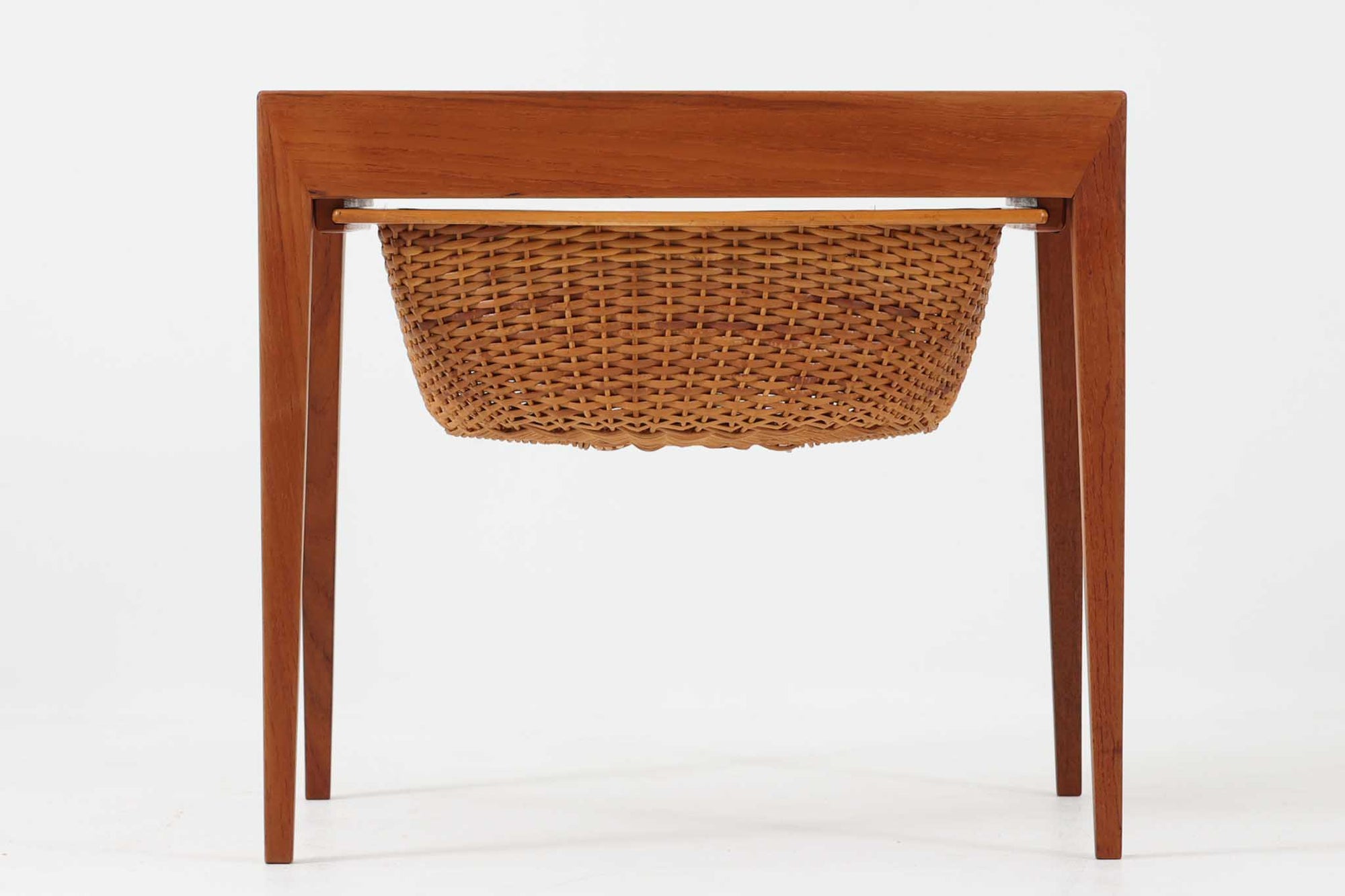 デンマークの名デザイナーSeverin Hansen Jr.が手掛け、Haslev社によって製造された北欧ビンテージのソーイングテーブルです。素材には温かみのあるチーク材が使用され、シャープな接合部とすっきりとしたテーパードレッグが洗練された佇まいを演出しています。特徴的な籐のバスケットは糸や道具類をたっぷりと収納でき、天板下のスライドトレイには仕切りがあり細かな道具の整理にも便利です。バスケットを支える木製レールの一部に欠けがありますが、使用には支障ありません。実用性と美しさを兼ね備えた一台で、裁縫道具の収納にはもちろん、サイドテーブルとしてもおすすめです。