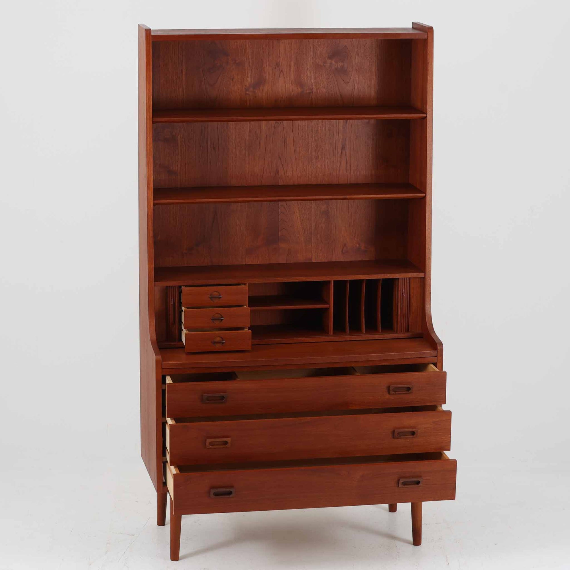 Johannes Sorth（ヨハネス・ソース）によるNexo Mobelfabrik社製のチーク材ディスプレイシェルフです。幅100cmと程よいサイズ感で、上段の棚は高さのある書籍やオブジェを飾るのに適しており、中央の蛇腹扉の内側には小引き出しや仕切りが備わり、細かな収納にも対応します。下段の3杯の引き出しは収納力に優れ、衣類や書類の整理に便利です。直線的なフォルムに温かみのあるチーク材の木目が映え、経年の艶が深みを増したビンテージらしい風合いを楽しめます。機能性と美観を兼ね備えた北欧家具の魅力が詰まった一台です。