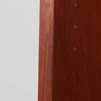 Johannes Sorth（ヨハネス・ソース）によるNexo Mobelfabrik社製のチーク材ディスプレイシェルフです。幅100cmと程よいサイズ感で、上段の棚は高さのある書籍やオブジェを飾るのに適しており、中央の蛇腹扉の内側には小引き出しや仕切りが備わり、細かな収納にも対応します。下段の3杯の引き出しは収納力に優れ、衣類や書類の整理に便利です。直線的なフォルムに温かみのあるチーク材の木目が映え、経年の艶が深みを増したビンテージらしい風合いを楽しめます。機能性と美観を兼ね備えた北欧家具の魅力が詰まった一台です。