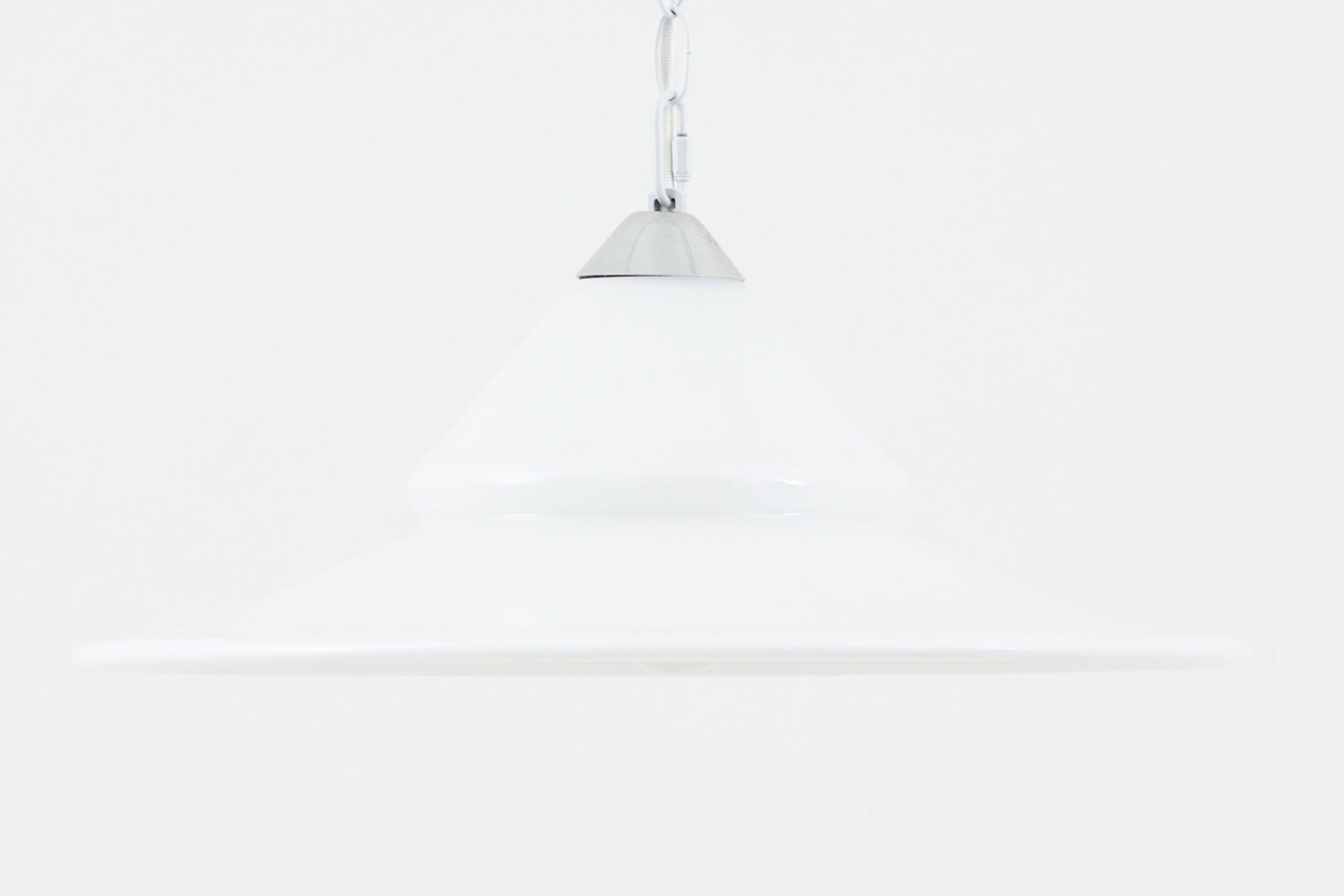 デンマークの名窯、Royal Copenhagen（ロイヤルコペンハーゲン）によるビンテージペンダントライト「Opus」。直径44cmのガラスシェードは、乳白色の滑らかな質感と優美な曲線を持ち、点灯時には柔らかな光をふんわりと拡散します。シェードの中央部にさりげない段差を設けたデザインは、シンプルながらも立体感があり、空間に洗練されたアクセントを加えます。金属パーツにはやや経年の使用感が見られますが、シェード自体は非常に良好な状態で、ガラスの透明感と清潔感を十分に感じられます。ダイニングやリビング、吹き抜けの空間など、幅広いインテリアにマッチし、北欧モダンな空間演出にぴったりの一灯です。