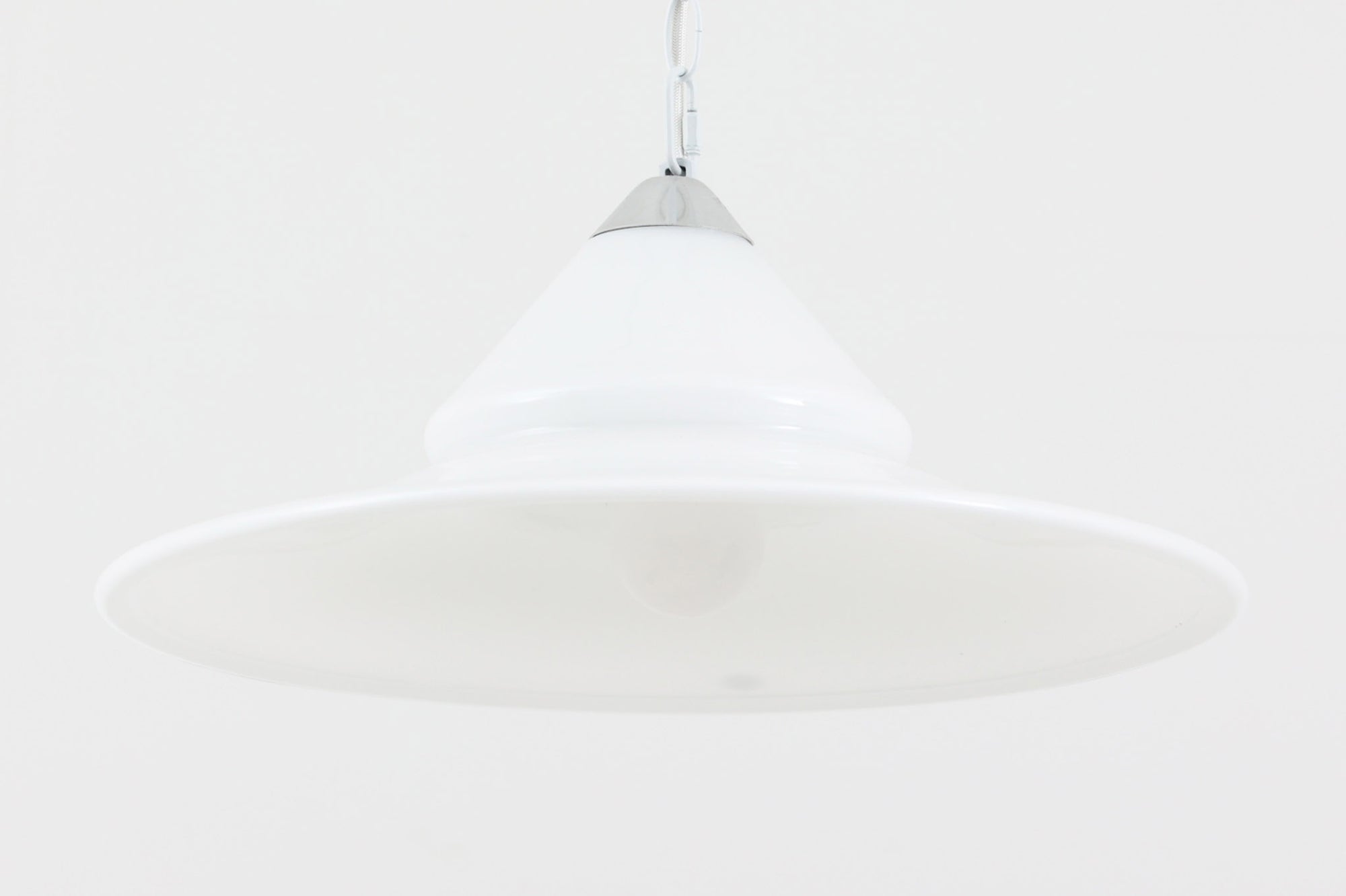 デンマークの名窯、Royal Copenhagen（ロイヤルコペンハーゲン）によるビンテージペンダントライト「Opus」。直径44cmのガラスシェードは、乳白色の滑らかな質感と優美な曲線を持ち、点灯時には柔らかな光をふんわりと拡散します。シェードの中央部にさりげない段差を設けたデザインは、シンプルながらも立体感があり、空間に洗練されたアクセントを加えます。金属パーツにはやや経年の使用感が見られますが、シェード自体は非常に良好な状態で、ガラスの透明感と清潔感を十分に感じられます。ダイニングやリビング、吹き抜けの空間など、幅広いインテリアにマッチし、北欧モダンな空間演出にぴったりの一灯です。
