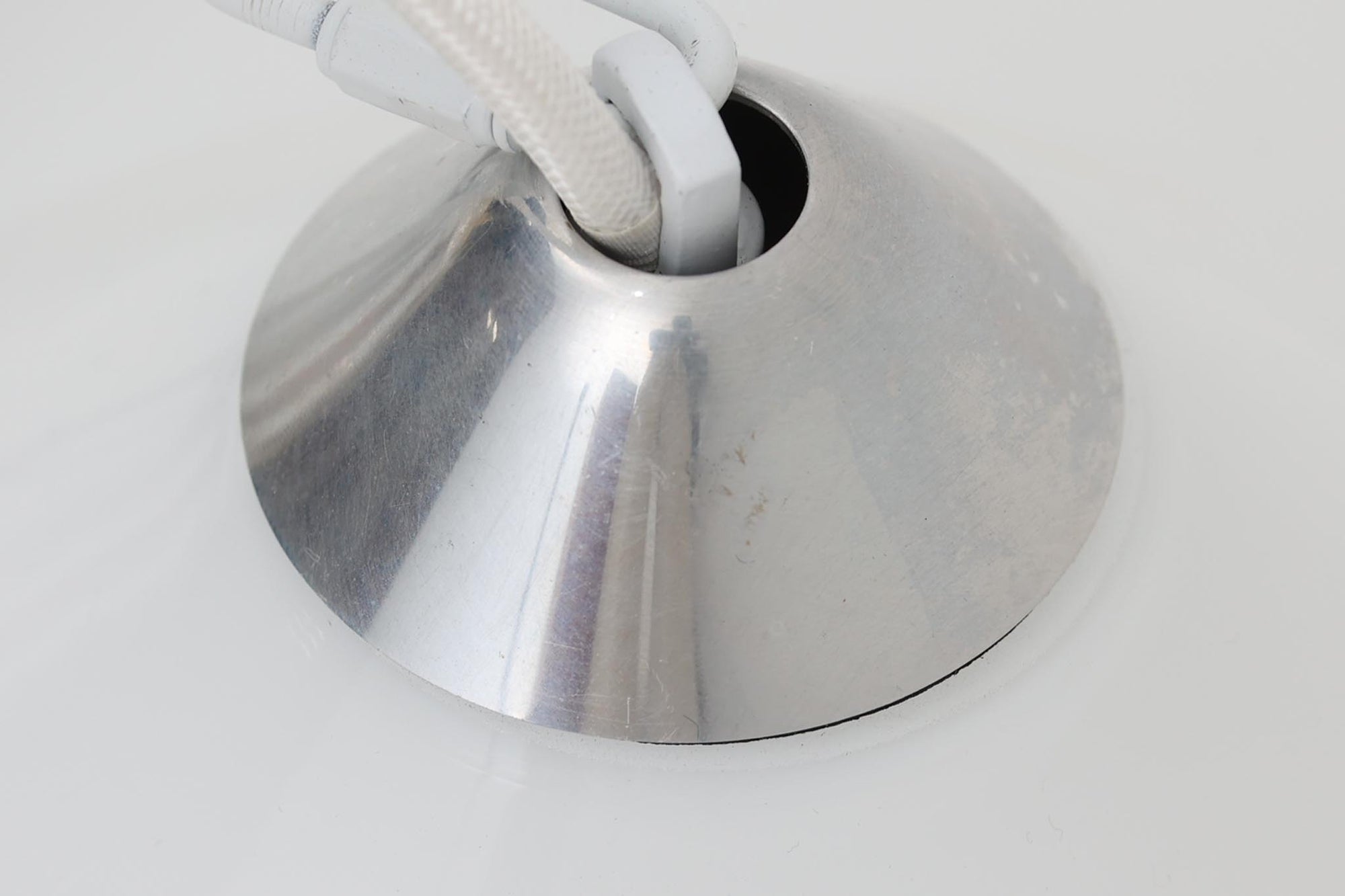 デンマークの名窯、Royal Copenhagen（ロイヤルコペンハーゲン）によるビンテージペンダントライト「Opus」。直径44cmのガラスシェードは、乳白色の滑らかな質感と優美な曲線を持ち、点灯時には柔らかな光をふんわりと拡散します。シェードの中央部にさりげない段差を設けたデザインは、シンプルながらも立体感があり、空間に洗練されたアクセントを加えます。金属パーツにはやや経年の使用感が見られますが、シェード自体は非常に良好な状態で、ガラスの透明感と清潔感を十分に感じられます。ダイニングやリビング、吹き抜けの空間など、幅広いインテリアにマッチし、北欧モダンな空間演出にぴったりの一灯です。