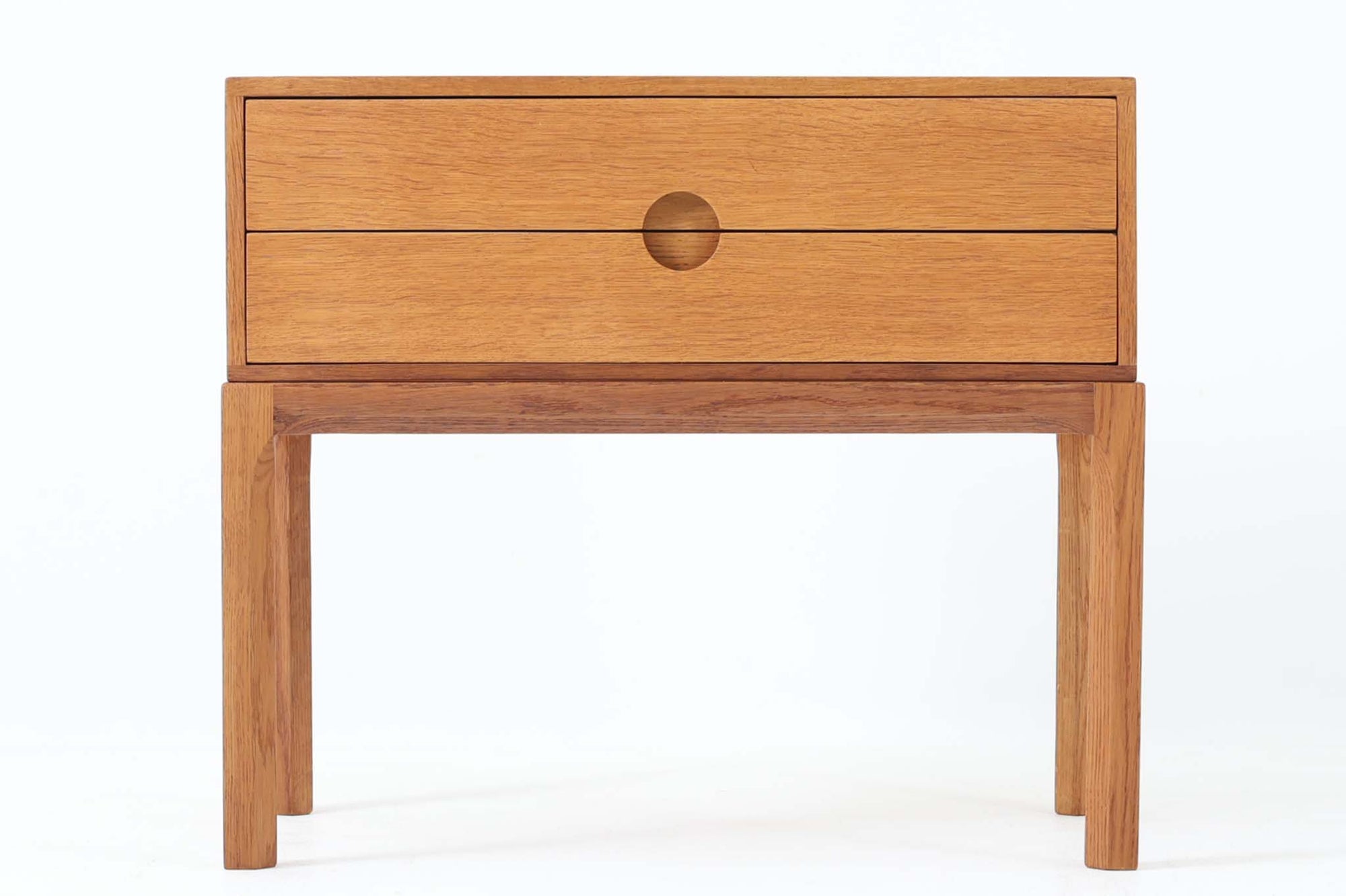 デンマークの巨匠Kai Kristiansen（カイ・クリスチャンセン）によってデザインされ、Aksel Kjersgaard（アクセル・ケアスゴー）社が製造したヴィンテージチェスト「No.384」です。素材には上質なオーク材が使用され、ナチュラルな木目とあたたかみのある色合いが魅力です。引き出しは円形のくり抜き取っ手がアクセントとなり、すっきりとした佇まいの中に北欧らしい機能美が感じられます。脚部には曲線を取り入れたデザインが施され、細部にまでこだわりが光る一台。ベッドサイドやリビング、玄関などさまざまなシーンで活躍します。裏面には「AKSEL KJERSGAARD ODDER」「mADE IN DENmARK」およびモデルナンバー「384」の刻印あり。シンプルでありながら存在感のある、北欧ヴィンテージの逸品です。
