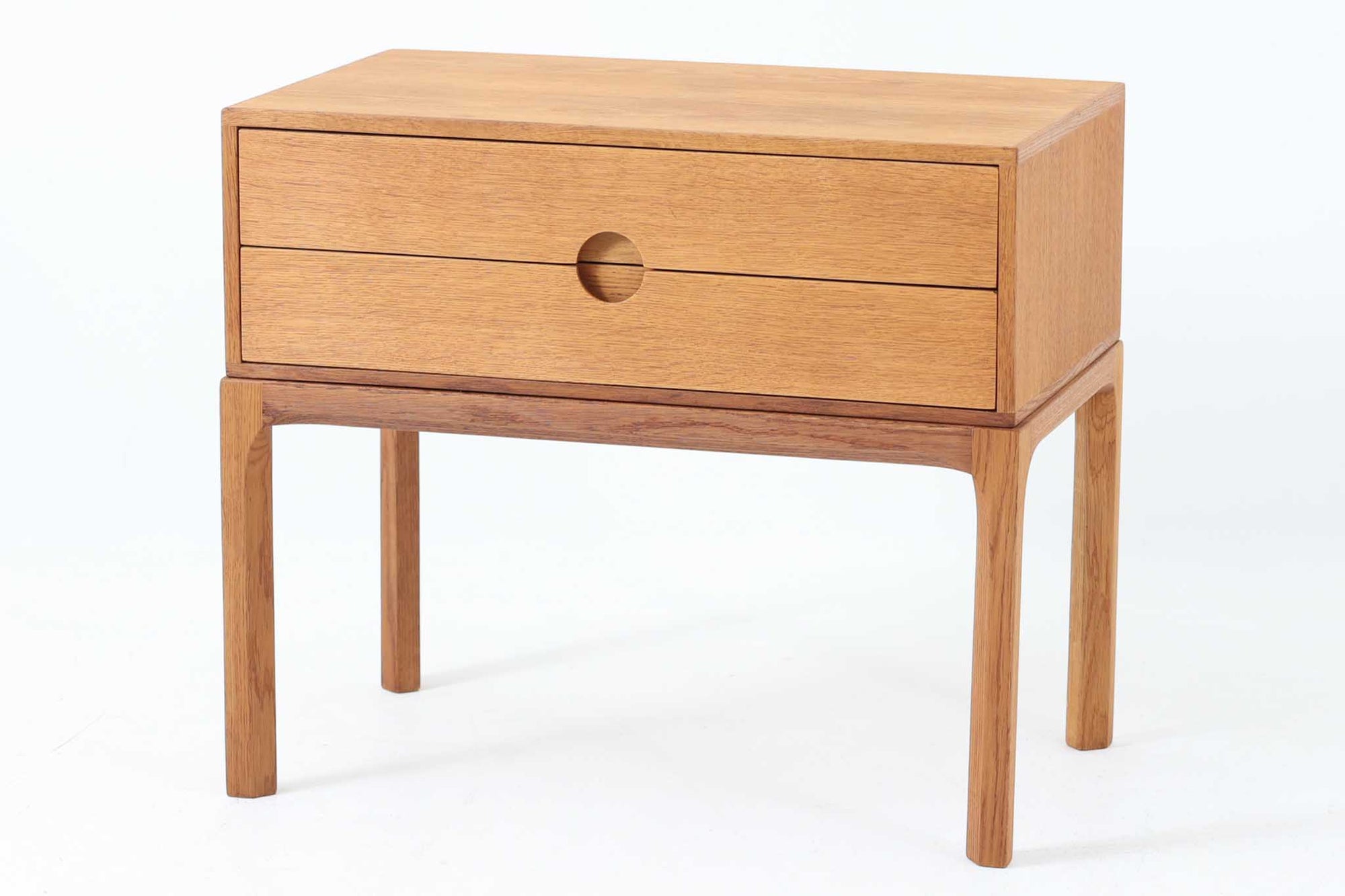 デンマークの巨匠Kai Kristiansen（カイ・クリスチャンセン）によってデザインされ、Aksel Kjersgaard（アクセル・ケアスゴー）社が製造したヴィンテージチェスト「No.384」です。素材には上質なオーク材が使用され、ナチュラルな木目とあたたかみのある色合いが魅力です。引き出しは円形のくり抜き取っ手がアクセントとなり、すっきりとした佇まいの中に北欧らしい機能美が感じられます。脚部には曲線を取り入れたデザインが施され、細部にまでこだわりが光る一台。ベッドサイドやリビング、玄関などさまざまなシーンで活躍します。裏面には「AKSEL KJERSGAARD ODDER」「mADE IN DENmARK」およびモデルナンバー「384」の刻印あり。シンプルでありながら存在感のある、北欧ヴィンテージの逸品です。