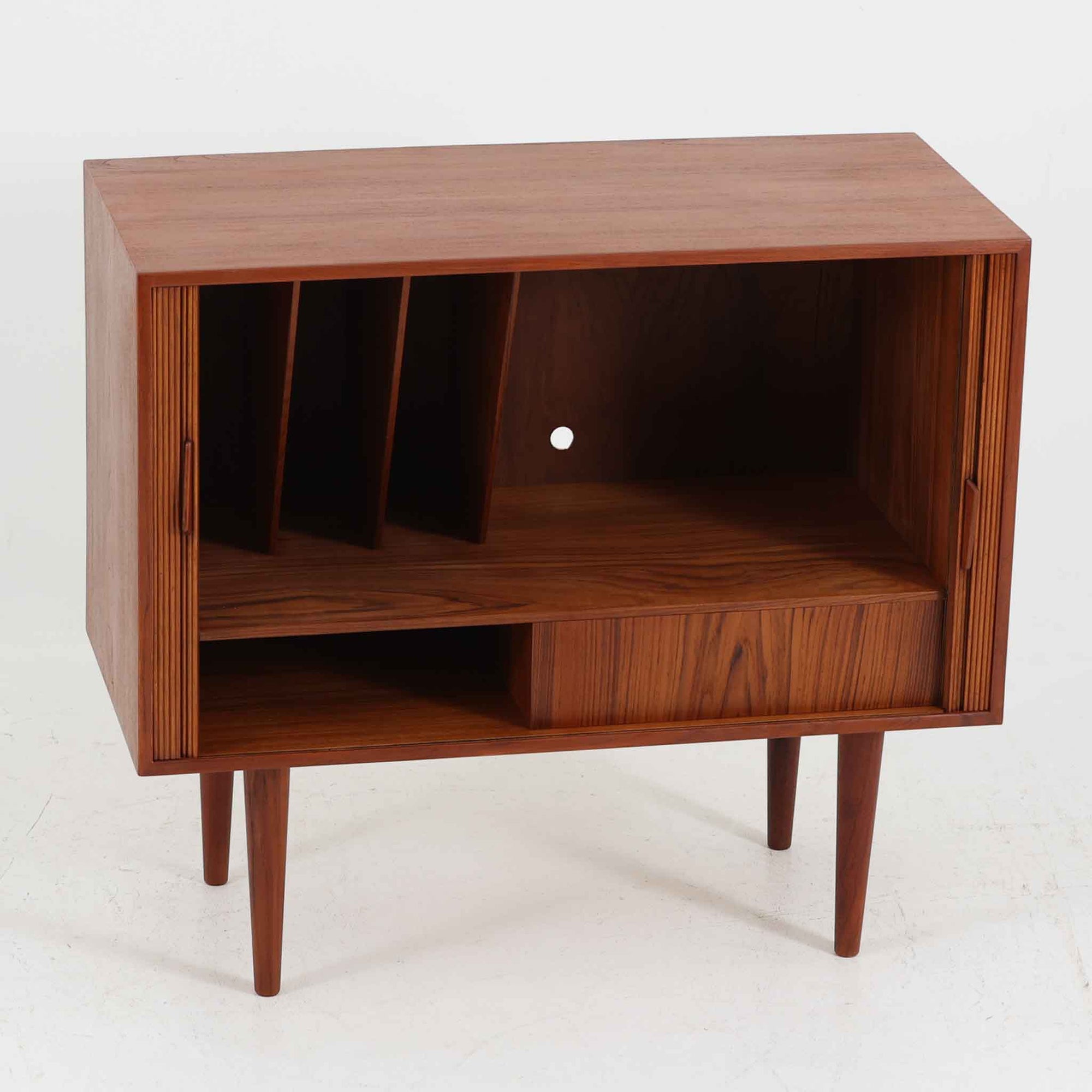Kai Kristiansen（カイ・クリスチャンセン）によるデザインで、Feldballes Mobelfabrik社から製造された蛇腹キャビネットです。繊細なスリットが並ぶチーク材のロールフロントは職人技が光る美しい仕上がりで、滑らかな開閉動作も魅力のひとつ。内部は仕切り板と小収納が備えられ、実用性にも優れています。右下の小収納部は前板のみが貼られた飾り構造で、内部に収納はありません。特注仕様と思われる希少な一点です。シンプルながら存在感があり、リビングやワークスペースにも調和する北欧ビンテージらしい端正な佇まいです。