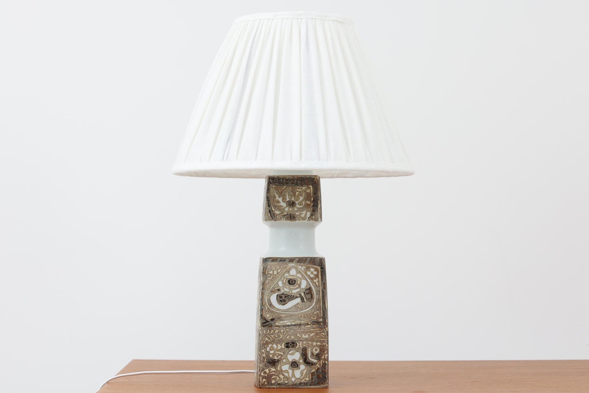 Royal Copenhagen製のベースが使用されたテーブルランプです。製造年数（1965〜1970年代）も少なく、現在では入手困難な希少モデルとなっています。現在の製造方法とは異なり、ファイアンス釜で作られた陶器ならではの独特な風合いが魅力で、ヴィンテージ品としての価値も高い一点です。ベースの柄は自然をモチーフとしたNils Thorssonによる人気のBACAシリーズで、職人の手作業によるフリーハンドで描かれているため、ひとつとして同じものが存在しない点もRoyal Copenhagenならではの魅力です。高さは約50cmとやや大きめで、インテリアのアクセントとしても存在感があり、オブジェのようにお部屋をおしゃれに演出してくれます。