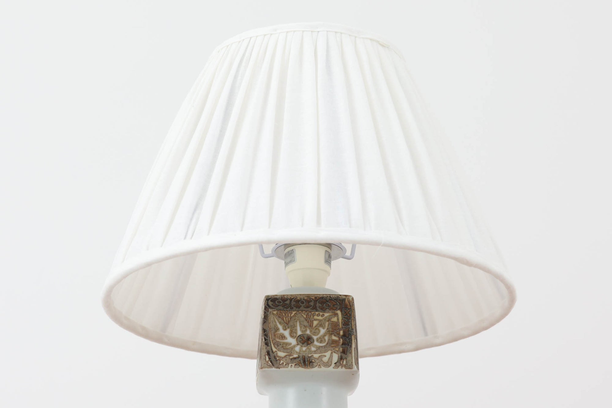 Royal Copenhagen製のベースが使用されたテーブルランプです。製造年数（1965〜1970年代）も少なく、現在では入手困難な希少モデルとなっています。現在の製造方法とは異なり、ファイアンス釜で作られた陶器ならではの独特な風合いが魅力で、ヴィンテージ品としての価値も高い一点です。ベースの柄は自然をモチーフとしたNils Thorssonによる人気のBACAシリーズで、職人の手作業によるフリーハンドで描かれているため、ひとつとして同じものが存在しない点もRoyal Copenhagenならではの魅力です。高さは約50cmとやや大きめで、インテリアのアクセントとしても存在感があり、オブジェのようにお部屋をおしゃれに演出してくれます。