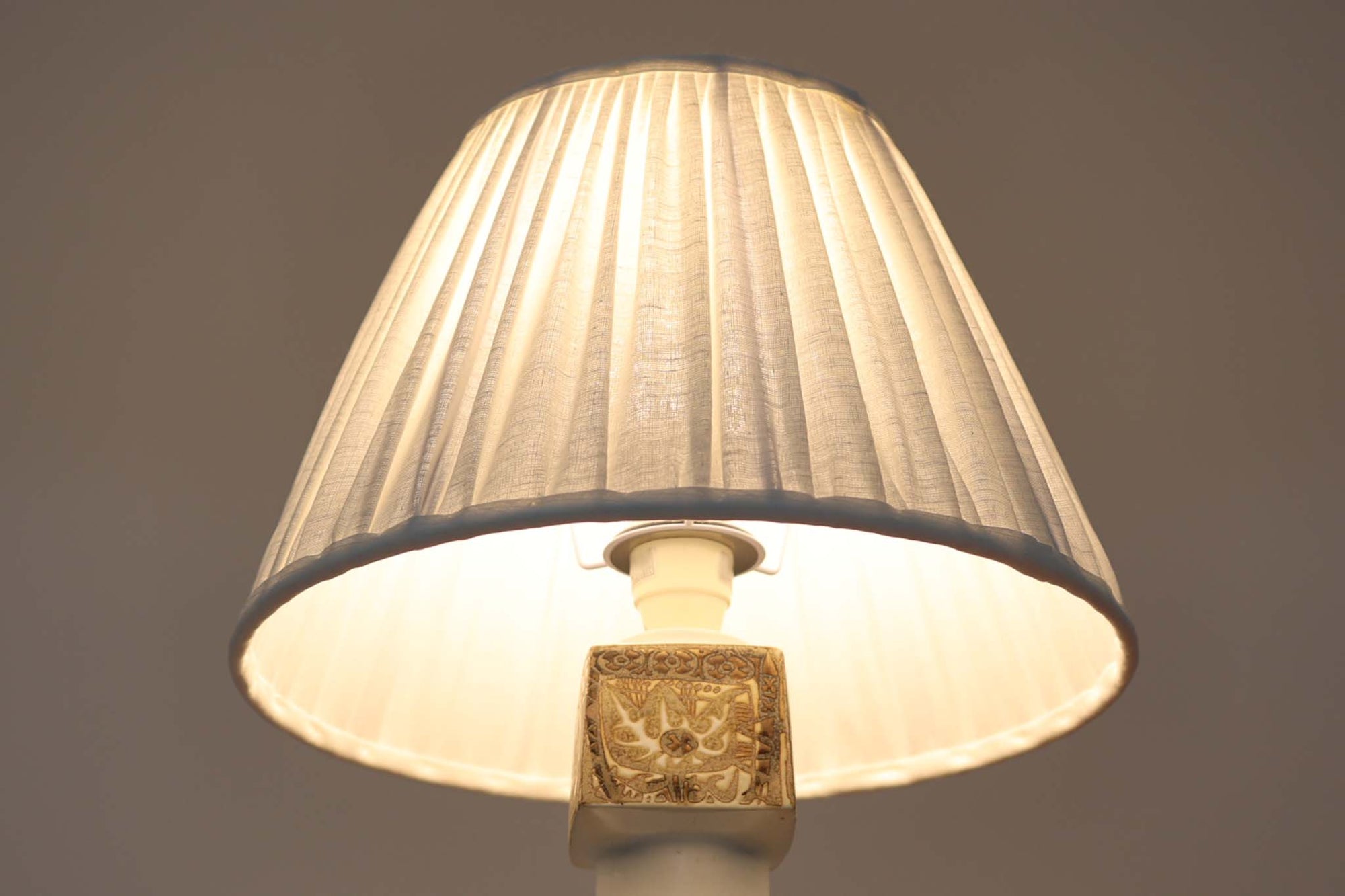 Royal Copenhagen製のベースが使用されたテーブルランプです。製造年数（1965〜1970年代）も少なく、現在では入手困難な希少モデルとなっています。現在の製造方法とは異なり、ファイアンス釜で作られた陶器ならではの独特な風合いが魅力で、ヴィンテージ品としての価値も高い一点です。ベースの柄は自然をモチーフとしたNils Thorssonによる人気のBACAシリーズで、職人の手作業によるフリーハンドで描かれているため、ひとつとして同じものが存在しない点もRoyal Copenhagenならではの魅力です。高さは約50cmとやや大きめで、インテリアのアクセントとしても存在感があり、オブジェのようにお部屋をおしゃれに演出してくれます。