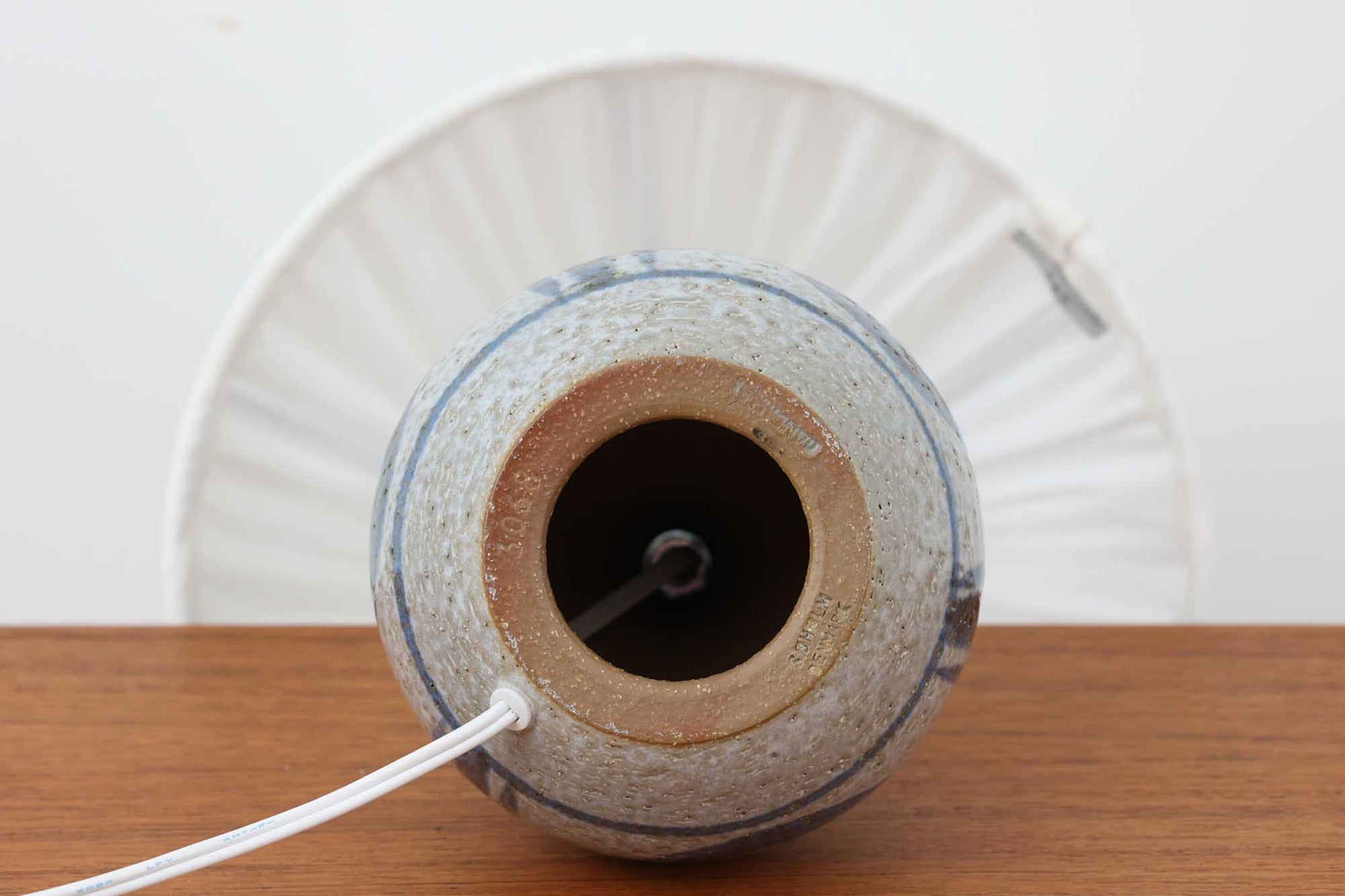 デンマーク・ボーンホルム島の陶器メーカーSOHOLMによるヴィンテージテーブルランプ。ざらりとした質感のある陶器ボディに、藍色を基調とした幾何学模様が手描きされています。丸みのあるフォルムが愛らしく、落ち着いた色合いは空間に優しく馴染みます。シェードは新品のリネン製に交換済みです。