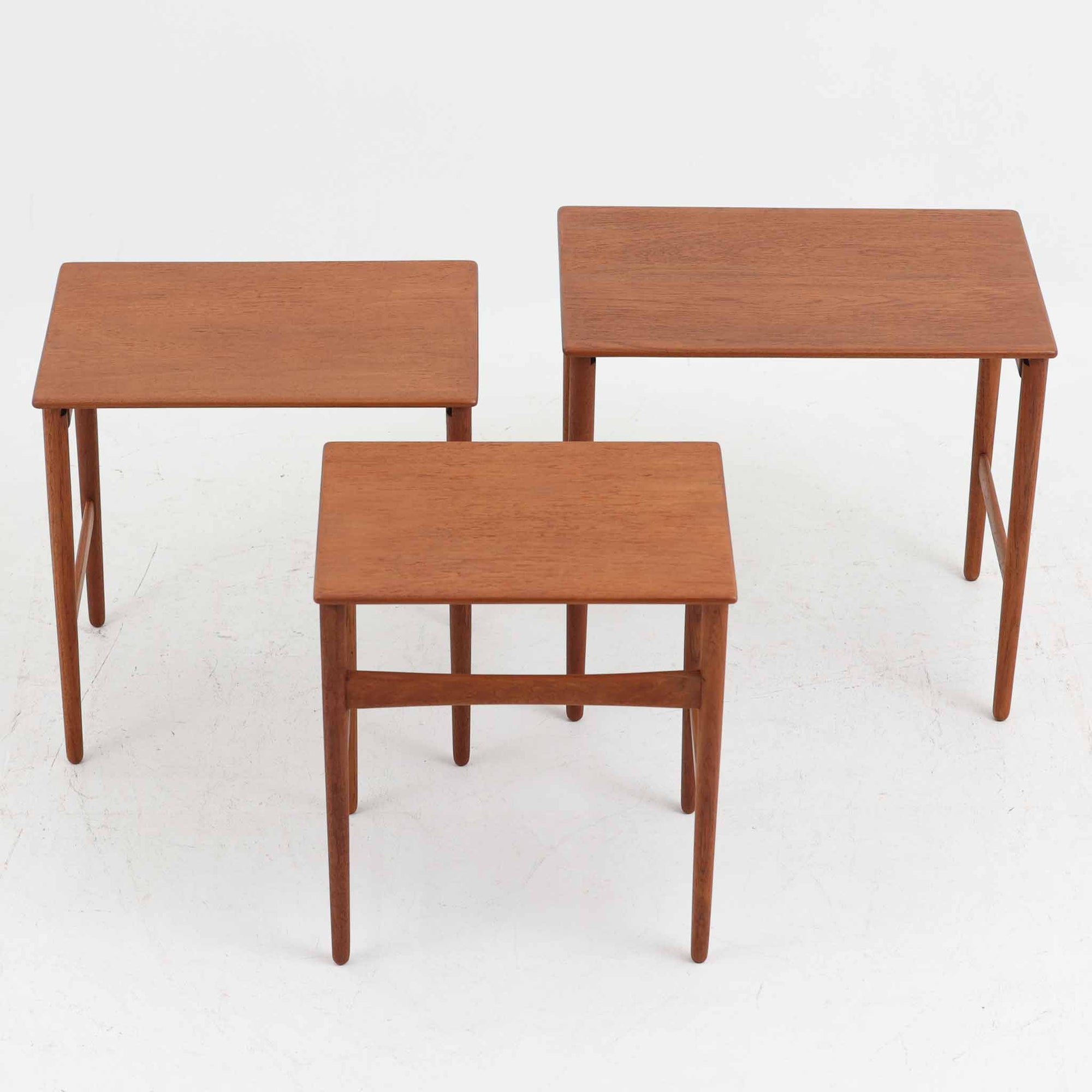 Hans J. Wegnerがデザインし、Andreas Tuck社より発表されたネストテーブル「AT40」です。チーク無垢材を贅沢に用いたシンプルで洗練されたフォルムは、使うほどに味わいを増し、経年変化による深みが楽しめます。大小3点が入れ子状に収まる構造で、省スペースでの収納性に優れながら必要な時にはサイドテーブルやティーテーブルとして自在に活躍します。細身の脚と滑らかな仕上げはウェグナーらしい職人技を感じさせ、日常に北欧デザインの機能美を取り入れられる逸品です。中でも本品はAT40の中でも全てがチーク無垢材で製作された希少なモデルであり、素材の質感を存分に堪能できる一点となっています。