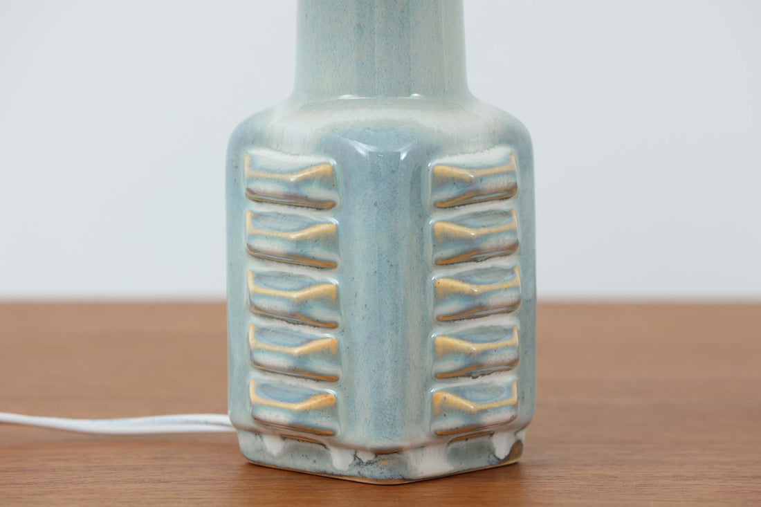 デンマーク・ボーンホルム島の陶器メーカーSoholm（スーホルム）で製作されたテーブルランプ。デザイナーはEinar Johansen（アイナー・ヨハンセン）。立体的なレリーフ模様と、ブルーグレーに淡くアイスブルーが重なる美しい釉薬の表情が特徴です。ユニークなフォルムも印象的で、置くだけで空間に存在感をもたらします。シェードは新品のリネン製を合わせています。北欧ヴィンテージらしい温もりと洗練を兼ね備えた一点です。